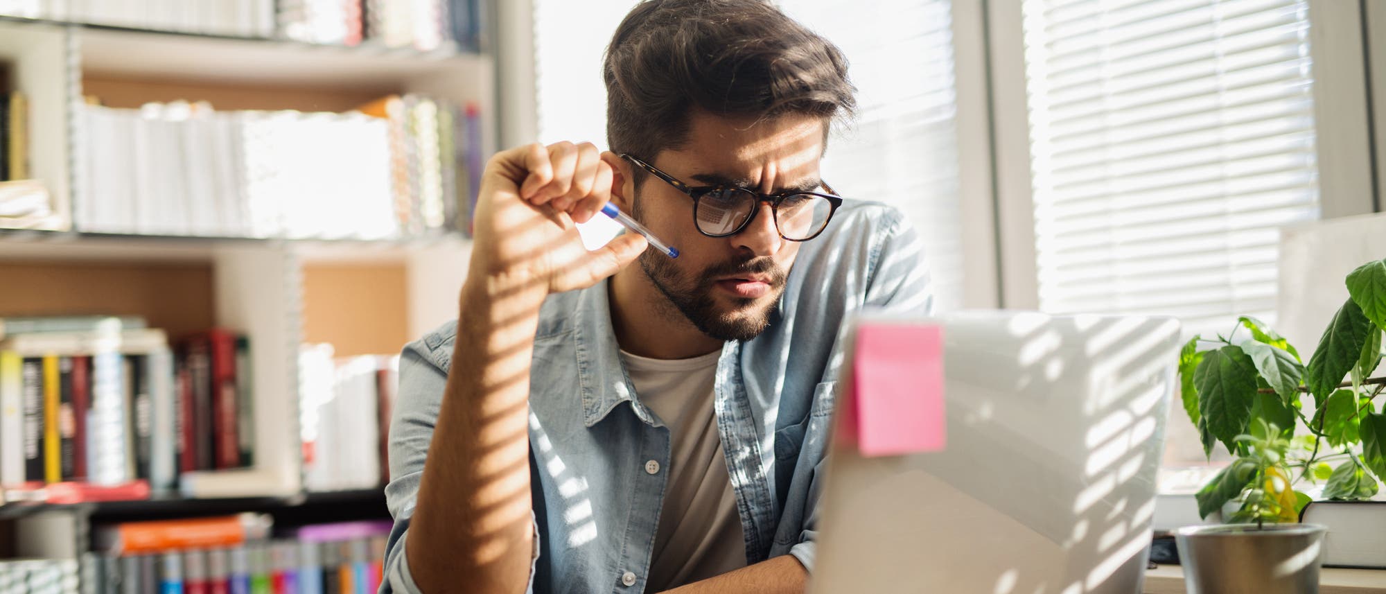 Ein junger Mann sitzt am Schreibtisch vorm Rechner, in die Arbeit vertieft