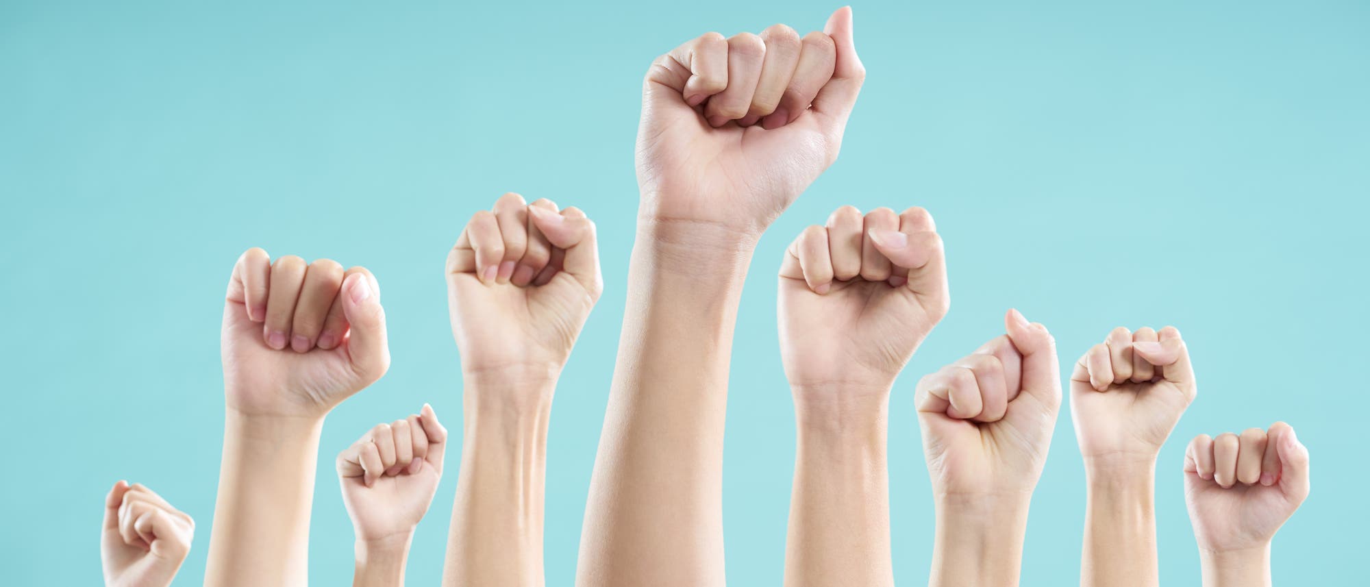 Mehrere erhobene F&auml;uste vor einem blauen Hintergrund, die Entschlossenheit und Solidarit&auml;t symbolisieren. Die H&auml;nde sind in verschiedenen Hautt&ouml;nen dargestellt, was betont, dass man &uuml;berall auf der Welt durch Unachtsamkeit Gliedma&szlig;en verlieren kann.