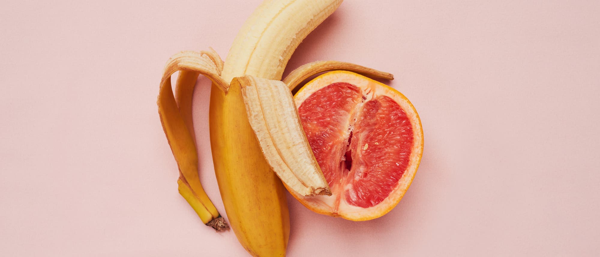 Banane und Grapefruit vor rosafarbenem Hintergrund