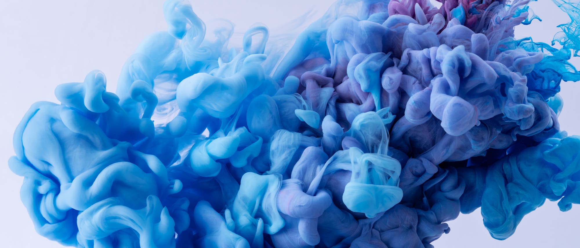 Eine abstrakte Fotografie zeigt eine dynamische Wolke aus blauen und violetten Farbtönen, die sich in einer fließenden Bewegung vermischen. Die Formen erinnern an Rauch oder Tinte, die sich in Wasser ausbreitet, und erzeugen ein Gefühl von Bewegung und Tiefe. Der Hintergrund ist hell und kontrastiert mit den lebendigen Farben im Vordergrund. Eine abstrakte Fotografie zeigt eine dynamische Wolke aus blauen und violetten Farbtönen, die sich in einer fließenden Bewegung vermischen. Die Formen erinnern an Rauch oder Tinte, die sich in Wasser ausbreitet, und erzeugen ein Gefühl von Bewegung und Tiefe. Der Hintergrund ist hell und kontrastiert mit den lebendigen Farben im Vordergrund.
