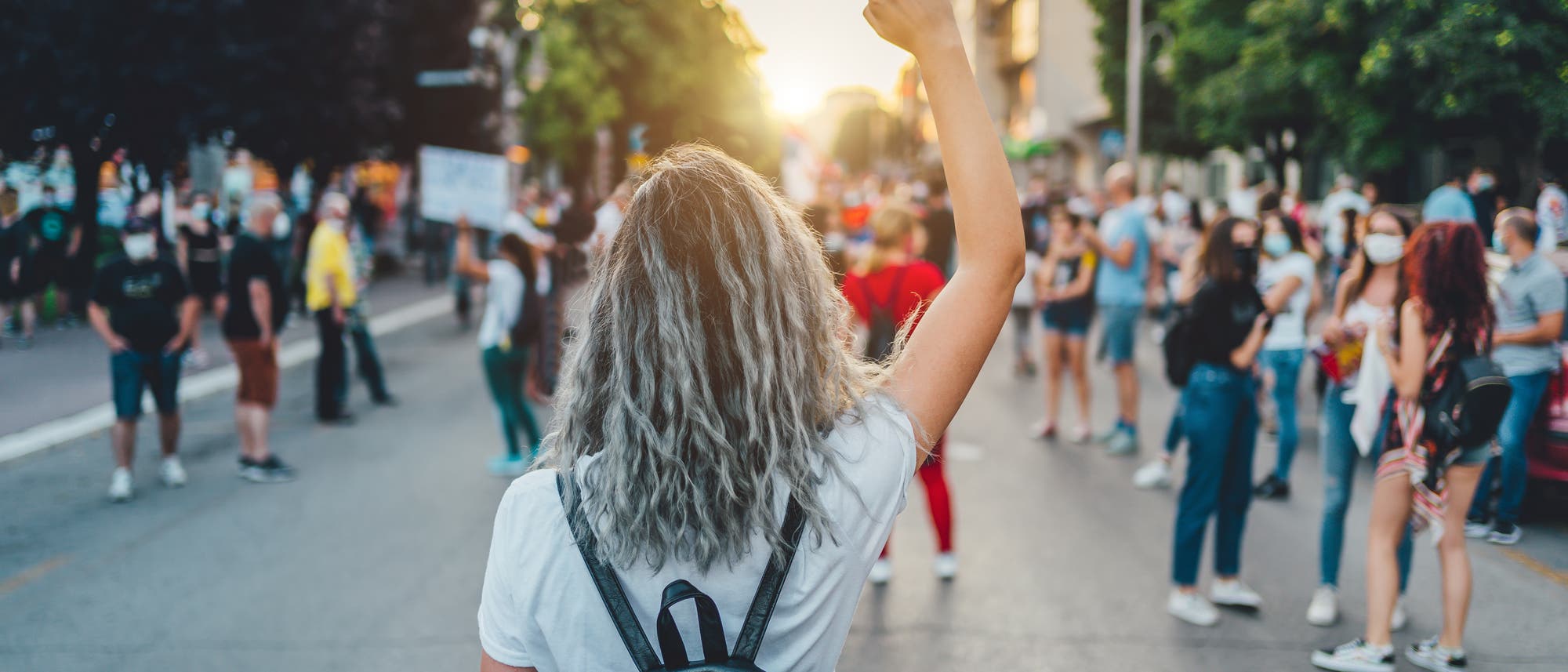 Eine Frau läuft einer Demonstration entgegen und streckt die Faust in die Höhe