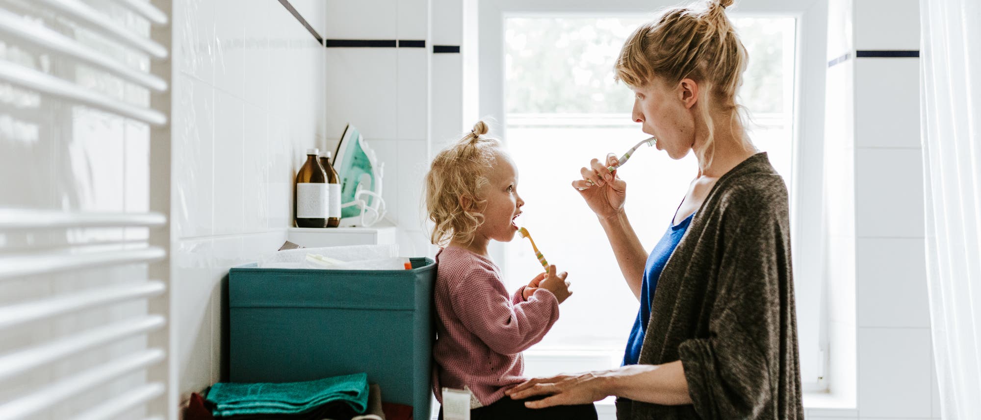 Mutter mit Kleinkind, die gemeinsam Zähne putzen