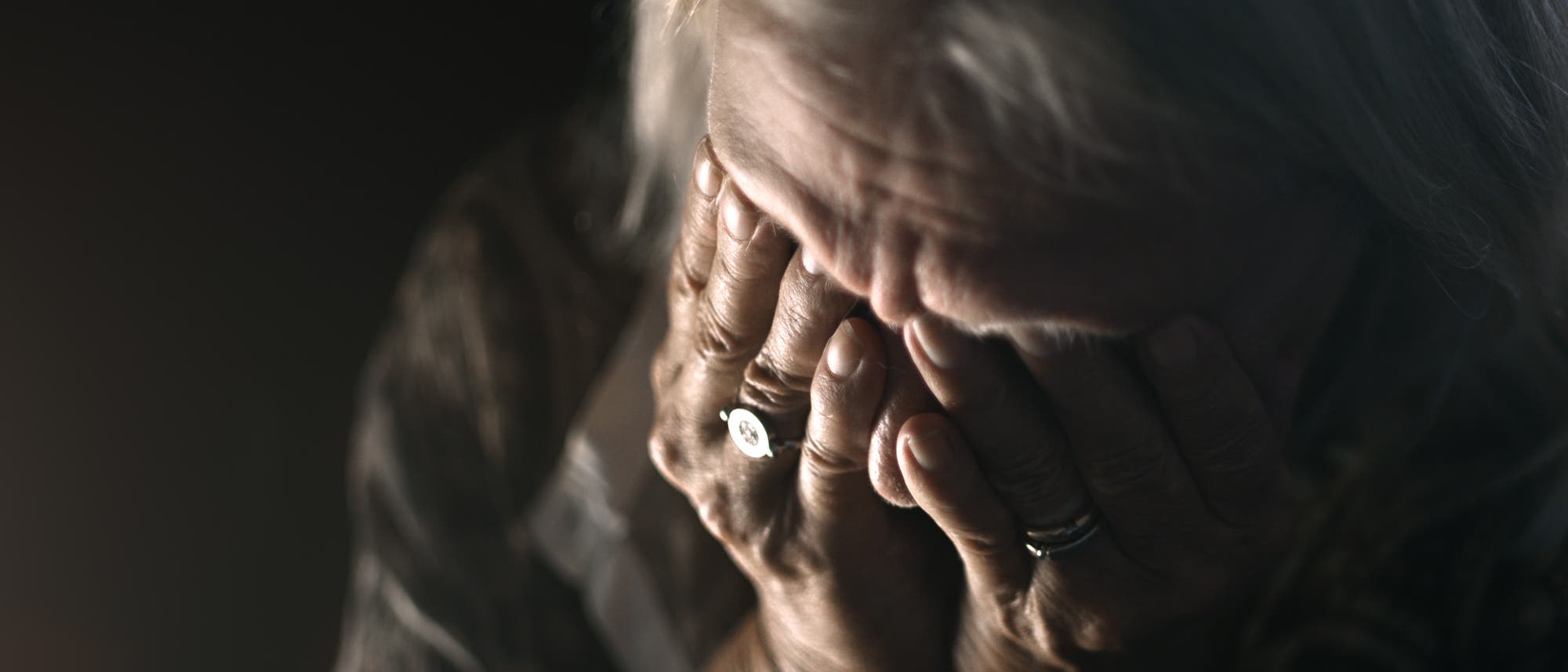 Alte Frau bedeckt ihr Gesicht mit den Händen