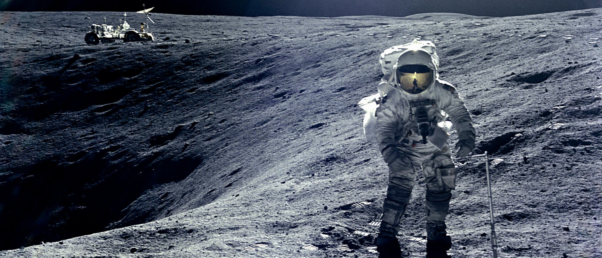 Ein Astronaut in einem Raumanzug steht auf der Mondoberfläche und hält ein Werkzeug. Im Hintergrund ist ein Mondfahrzeug zu sehen. Die Landschaft ist karg und von Kratern geprägt. Der Himmel ist dunkel und sternenlos. Ein Astronaut in einem Raumanzug steht auf der Mondoberfläche und hält ein Werkzeug. Im Hintergrund ist ein Mondfahrzeug zu sehen. Die Landschaft ist karg und von Kratern geprägt. Der Himmel ist dunkel und sternenlos.