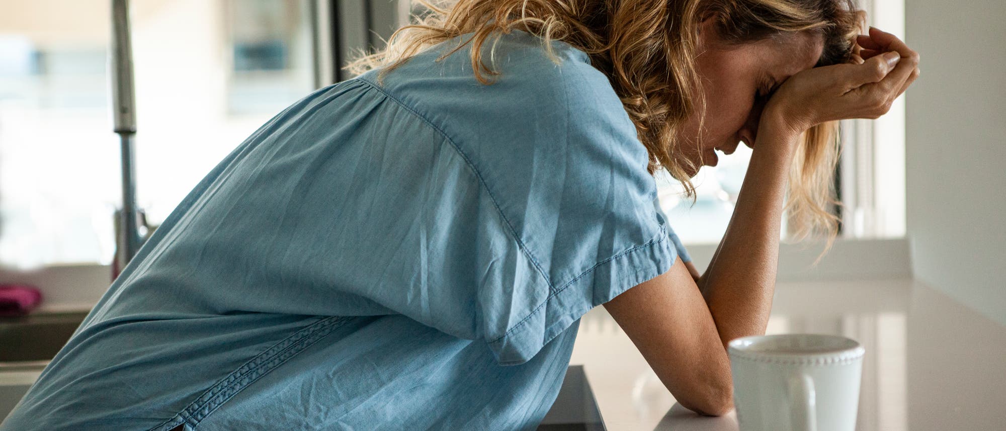 Frau mit Migr&auml;ne st&uuml;tzt Kopf in die H&auml;nde