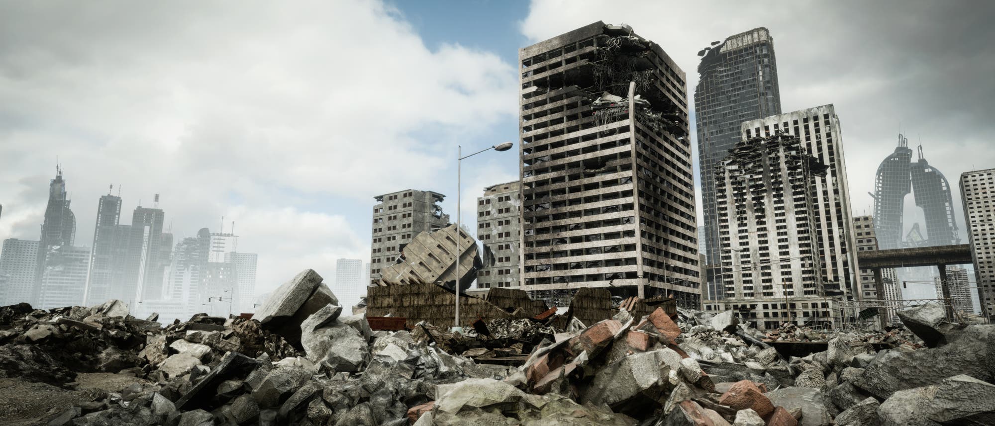 Eine verlassene Stadtlandschaft mit zerstörten Hochhäusern und Trümmern im Vordergrund. Der Himmel ist bewölkt, und die Szenerie wirkt düster und post-apokalyptisch. Die Gebäude sind stark beschädigt, mit sichtbaren Löchern und eingestürzten Teilen. Im Hintergrund sind weitere Wolkenkratzer zu sehen, die ebenfalls beschädigt sind. Die Umgebung ist von Schutt und Betonbrocken geprägt. Eine verlassene Stadtlandschaft mit zerstörten Hochhäusern und Trümmern im Vordergrund. Der Himmel ist bewölkt, und die Szenerie wirkt düster und post-apokalyptisch. Die Gebäude sind stark beschädigt, mit sichtbaren Löchern und eingestürzten Teilen. Im Hintergrund sind weitere Wolkenkratzer zu sehen, die ebenfalls beschädigt sind. Die Umgebung ist von Schutt und Betonbrocken geprägt.