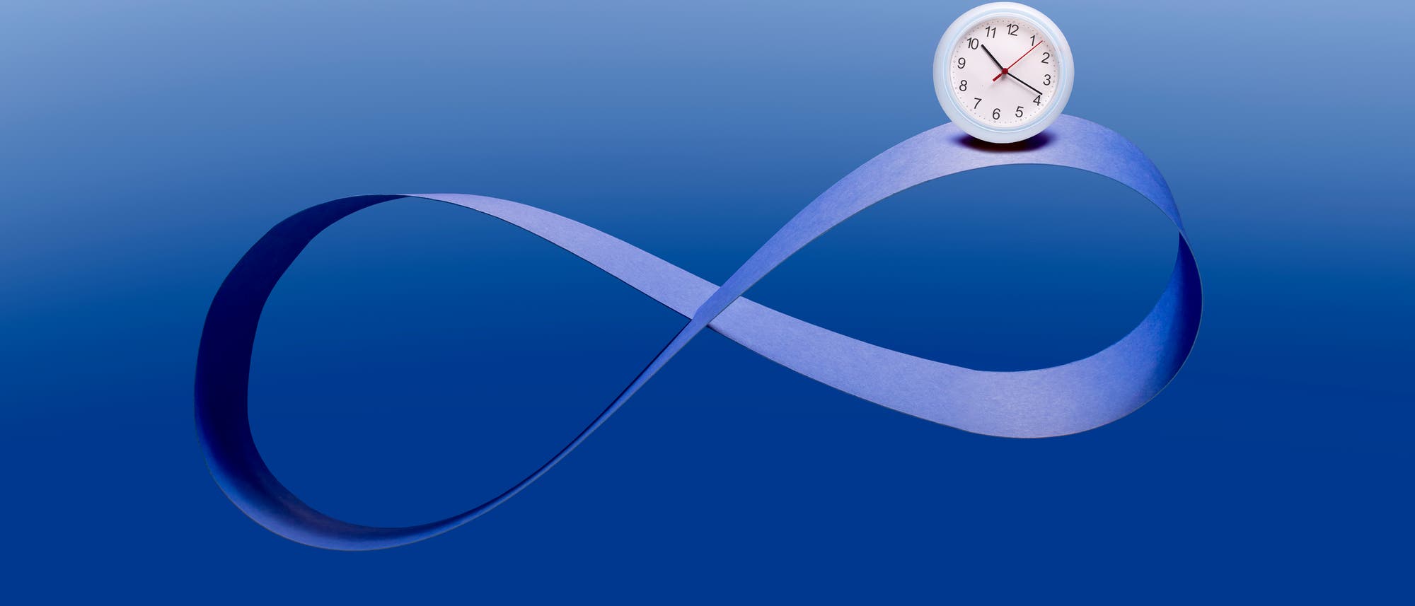 Eine Illustration eines Möbiusbandes, das in Form einer Unendlichkeitsschleife gestaltet ist. Rechts auf dem Band befindet sich eine weiße analoge Uhr, die 10:18 Uhr zeigt. Hintergrund und Möbiusband sind in verschiedenen Blautönen gehalten. Eine Illustration eines Möbiusbandes, das in Form einer Unendlichkeitsschleife gestaltet ist. Rechts auf dem Band befindet sich eine weiße analoge Uhr, die 10:18 Uhr zeigt. Hintergrund und Möbiusband sind in verschiedenen Blautönen gehalten.