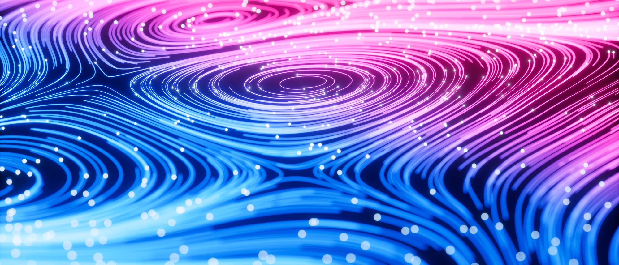 Abstrakte Darstellung von flie&szlig;enden Linien in Blau- und Pinkt&ouml;nen, die Wirbel und Wellenmuster bilden. Kleine wei&szlig;e Punkte sind &uuml;ber das Bild verteilt, was einen dynamischen und energetischen Effekt erzeugt. Die Komposition erinnert an Str&ouml;mungsmuster oder magnetische Felder.