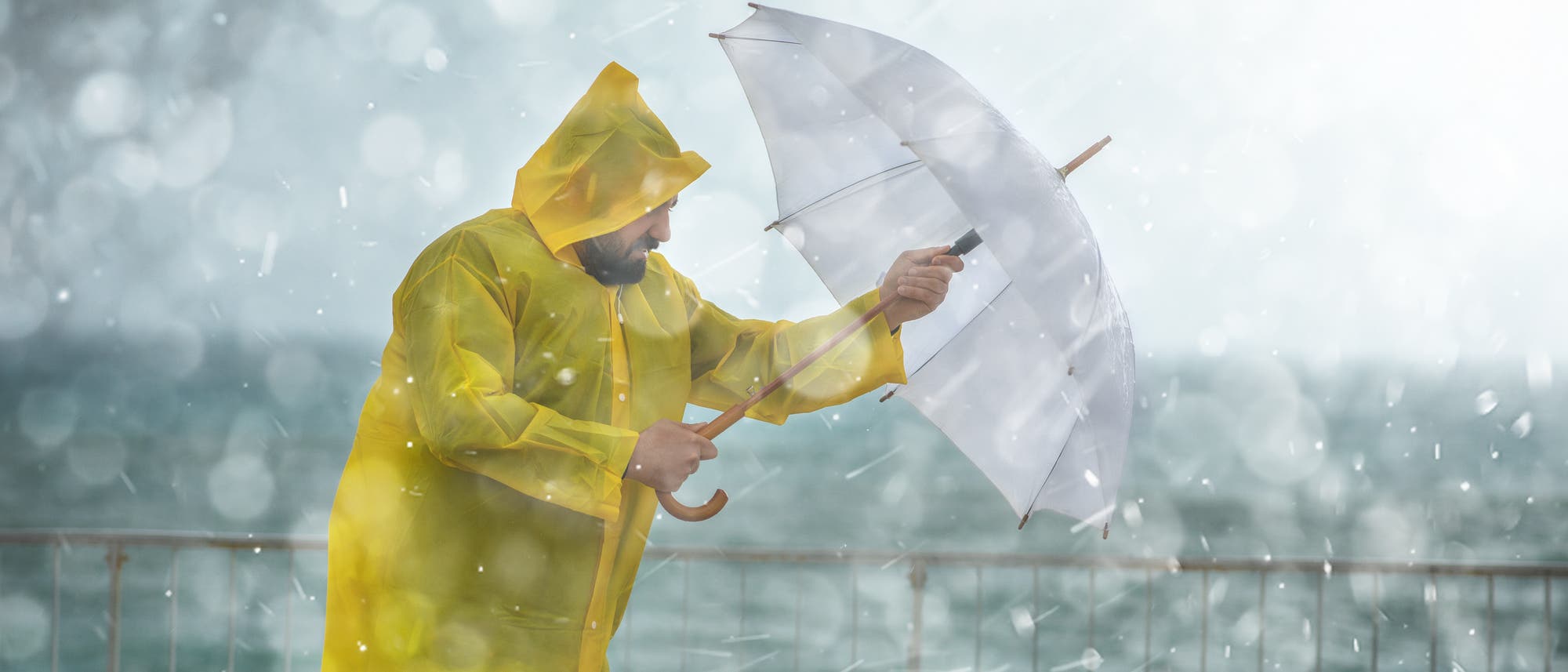 Ein Mann mit gelbem Mantel steht im Regen
