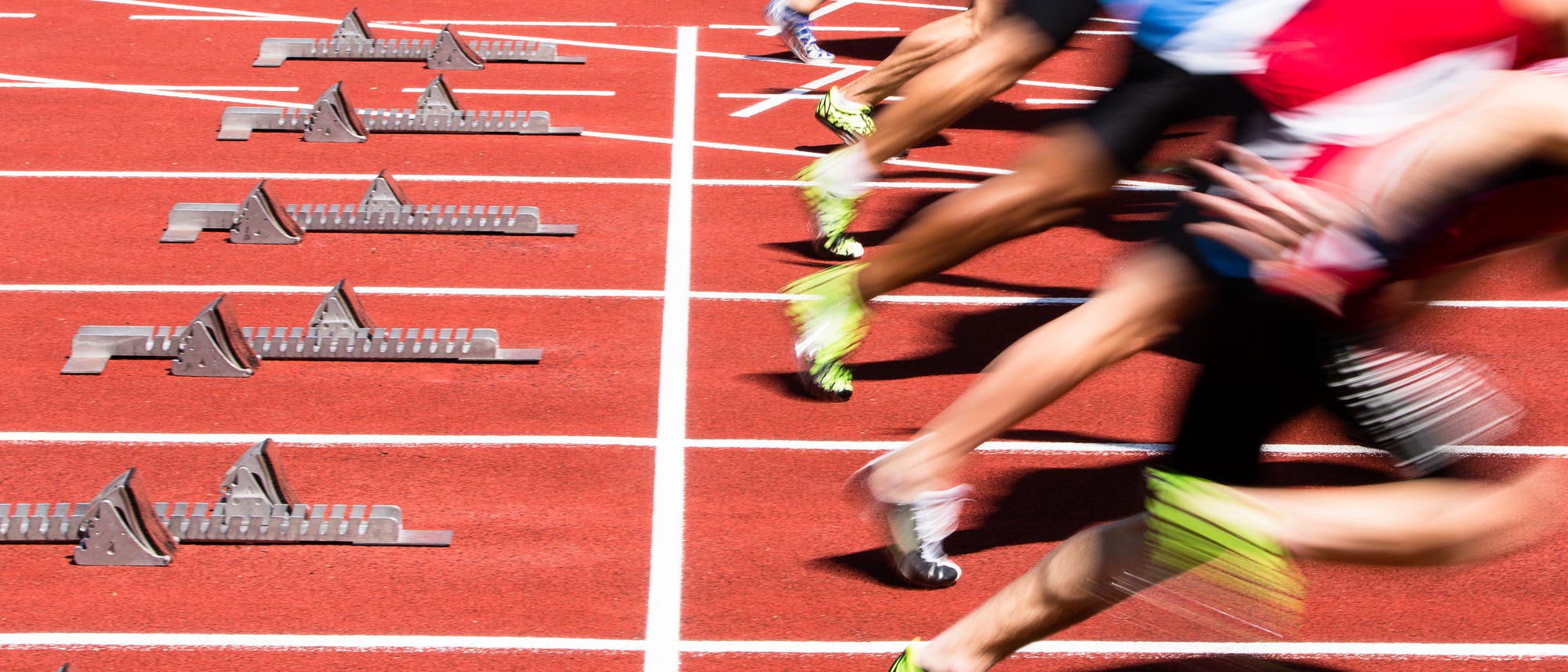 Start eines Sprints auf der Tartanbahn, 6 Sprinter sind soeben gestartet unnd leicht verwischt sichtbar