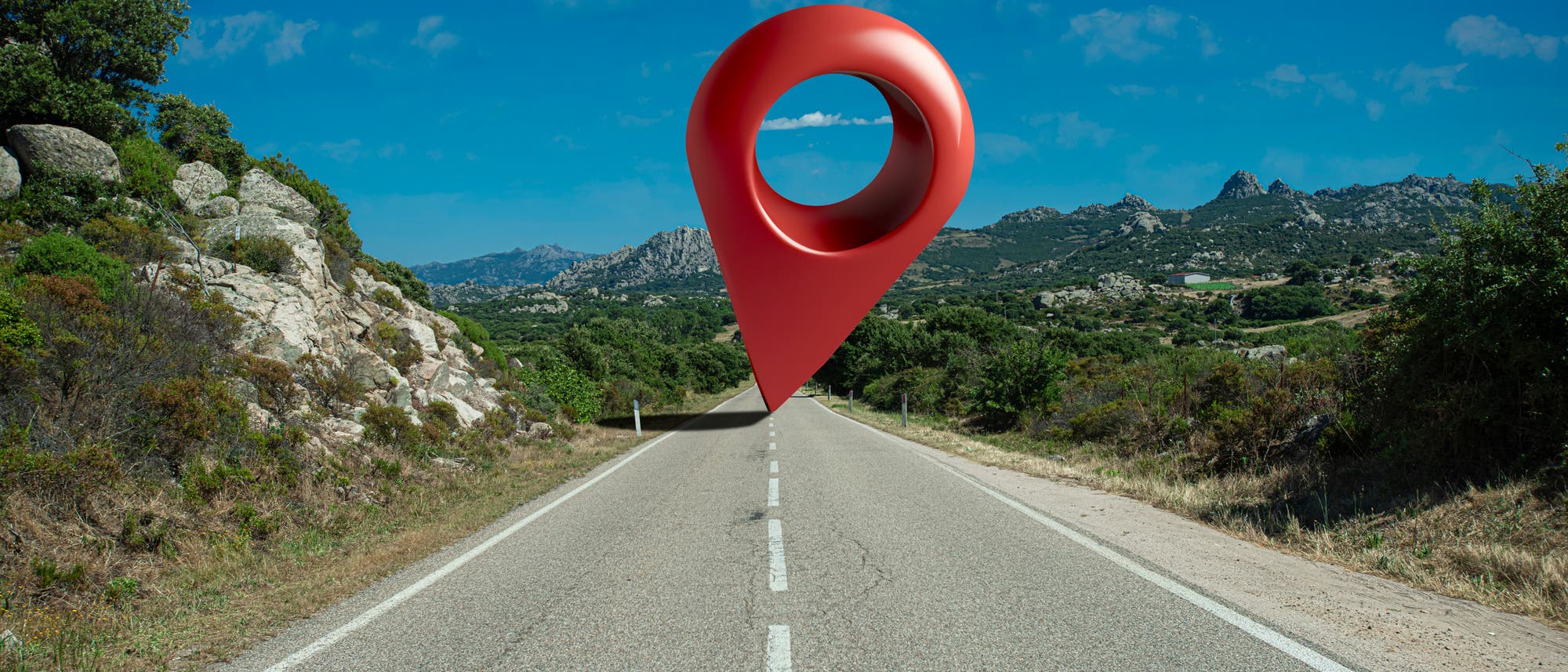 Überdimensionierter Navi-Pin auf einer Landstraße in Italien Überdimensionierter Navi-Pin auf einer Landstraße in Italien