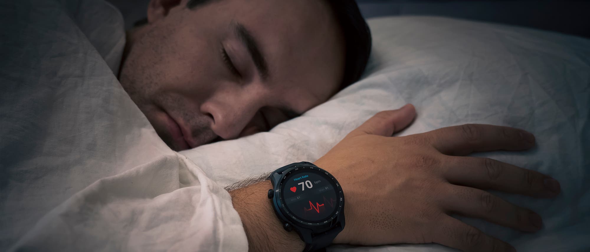 Ein Mann mit einer Smartwatch am Handgelenk liegt im Bett und tut so, als würde er schlafen. Ein Mann mit einer Smartwatch am Handgelenk liegt im Bett und tut so, als würde er schlafen.