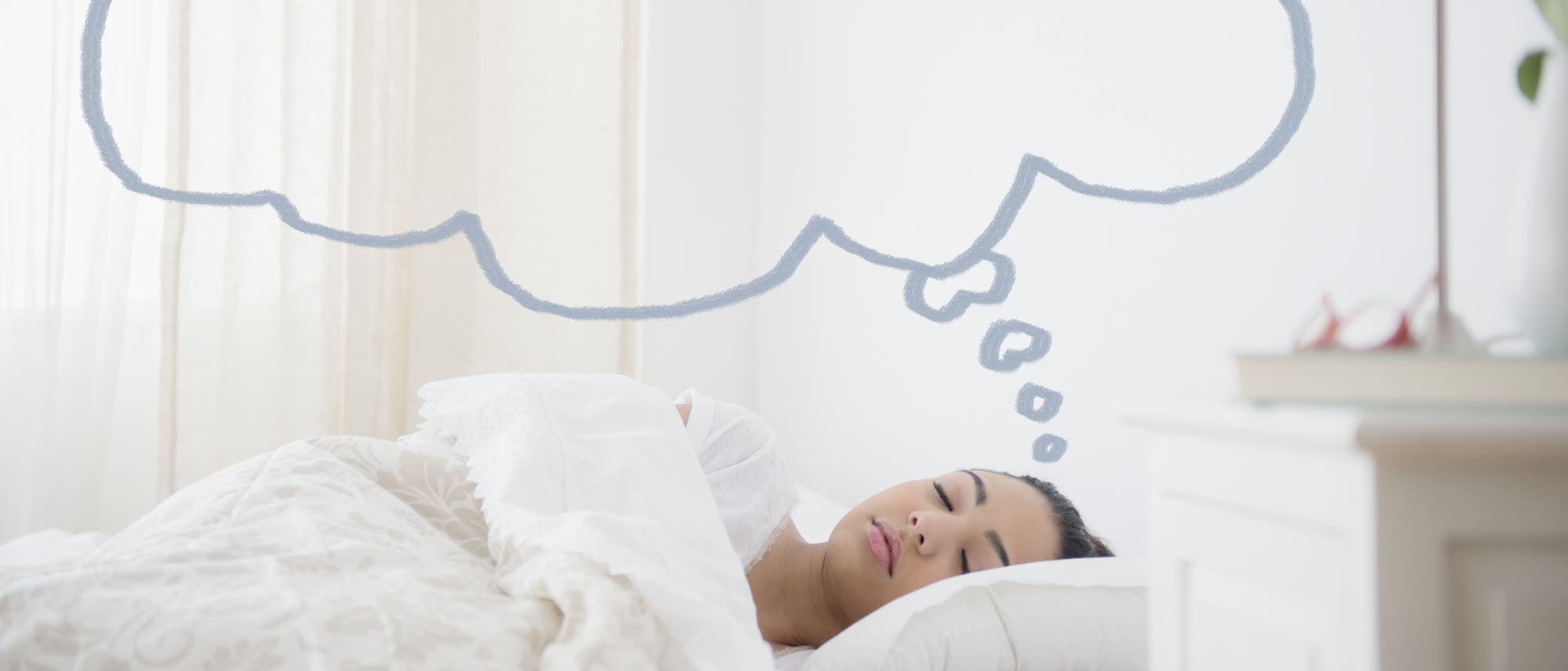 Eine Person schläft friedlich in einem Bett mit weißer Bettwäsche. Über ihrem Kopf ist eine gezeichnete Gedankenblase zu sehen, die auf Träume hinweist. Im Vordergrund steht ein Nachttisch mit einem Buch und einer Brille. Sanftes Tageslicht fällt durch einen Vorhang ins Zimmer. Eine Person schläft friedlich in einem Bett mit weißer Bettwäsche. Über ihrem Kopf ist eine gezeichnete Gedankenblase zu sehen, die auf Träume hinweist. Im Vordergrund steht ein Nachttisch mit einem Buch und einer Brille. Sanftes Tageslicht fällt durch einen Vorhang ins Zimmer.
