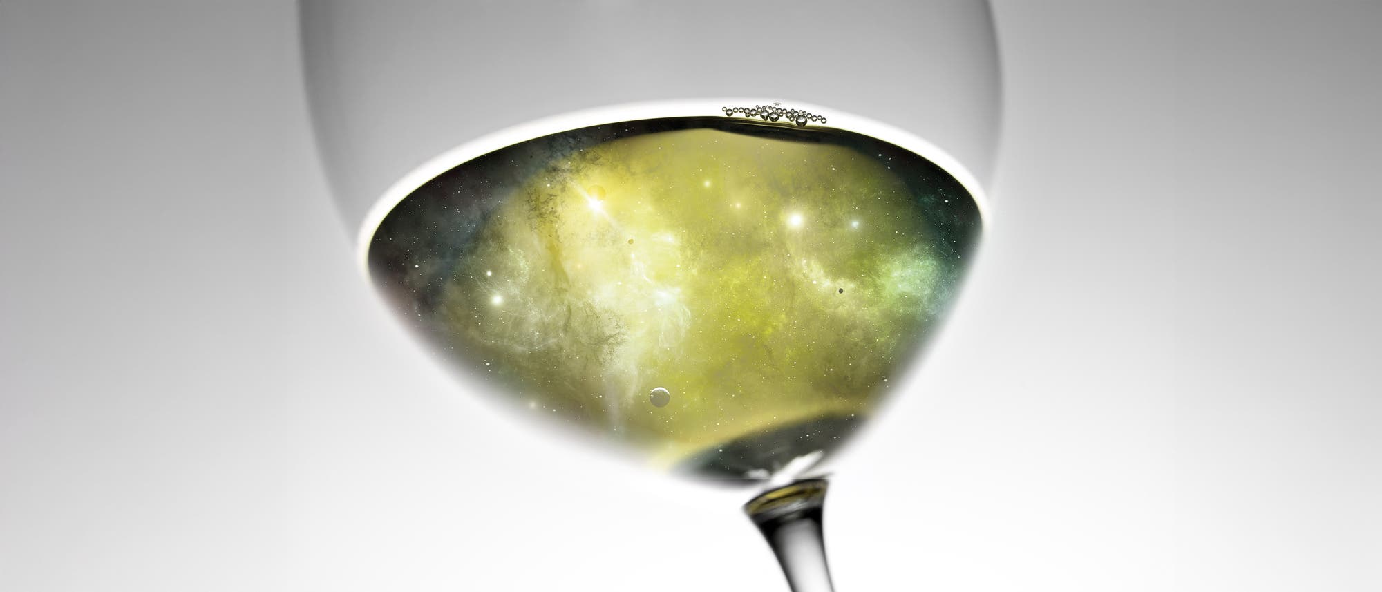 Ein Weinglas, das ein Bild eines leuchtenden, nebligen Weltraumnebels mit funkelnden Sternen und Planeten enth&auml;lt. Die Darstellung kombiniert die Eleganz eines Glases mit der Weite des Universums, wodurch ein surrealer Effekt entsteht. Der Hintergrund ist schlicht und lenkt den Fokus auf die faszinierende Mischung aus Astronomie und Alltagsobjekt.