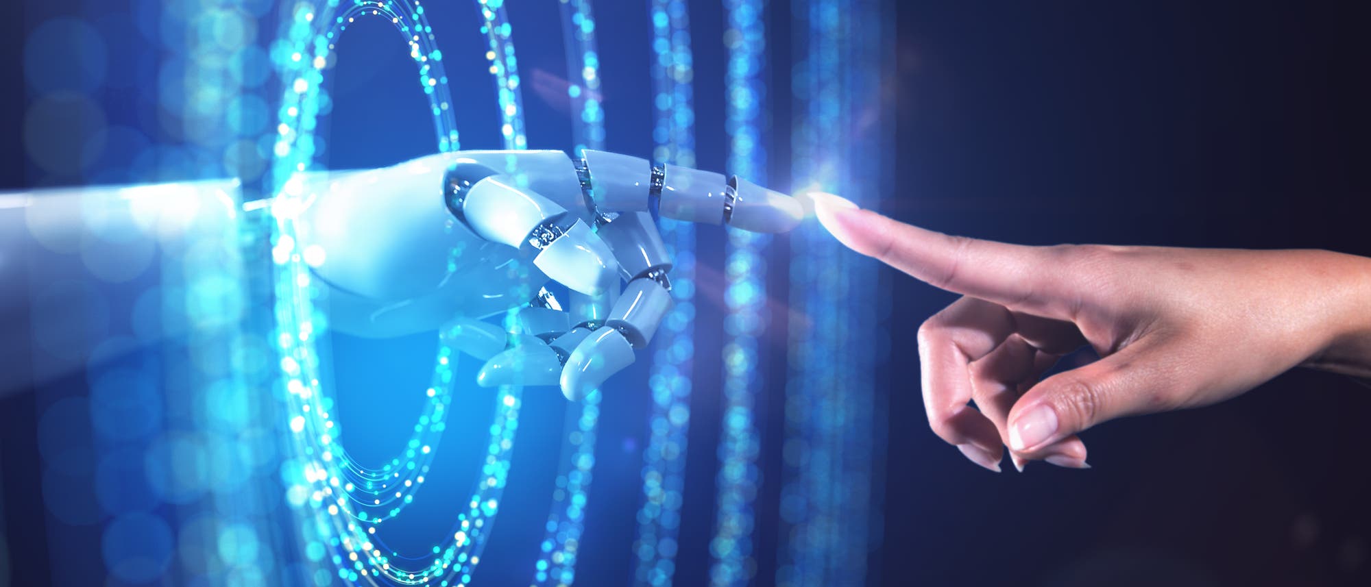 Eine menschliche Hand und eine Roboterhand berühren sich mit den Fingerspitzen vor einem Hintergrund aus leuchtenden, blauen Lichtkreisen. Die Szene symbolisiert die Verbindung zwischen Mensch und Technologie.