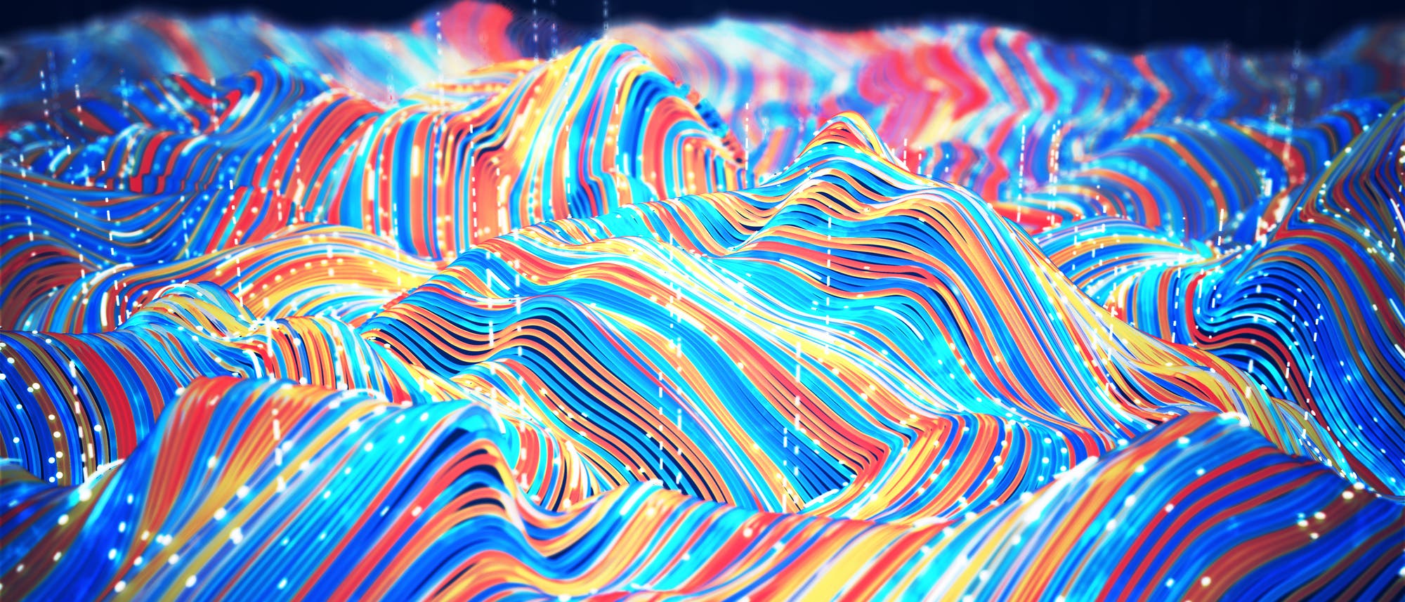 Eine 3-D-Darstellung zeigt eine wellenförmige Landschaft aus bunten, geschwungenen Linien in Blau, Rot, Gelb und Orange. Die Linien verlaufen parallel und erzeugen ein dynamisches Muster, das an topografische Karten erinnert. Kleine, leuchtende Punkte sind entlang der Linien verteilt, was einen digitalen oder technologischen Eindruck vermittelt. Der Hintergrund ist dunkel, wodurch die Farben der Linien hervorgehoben werden.