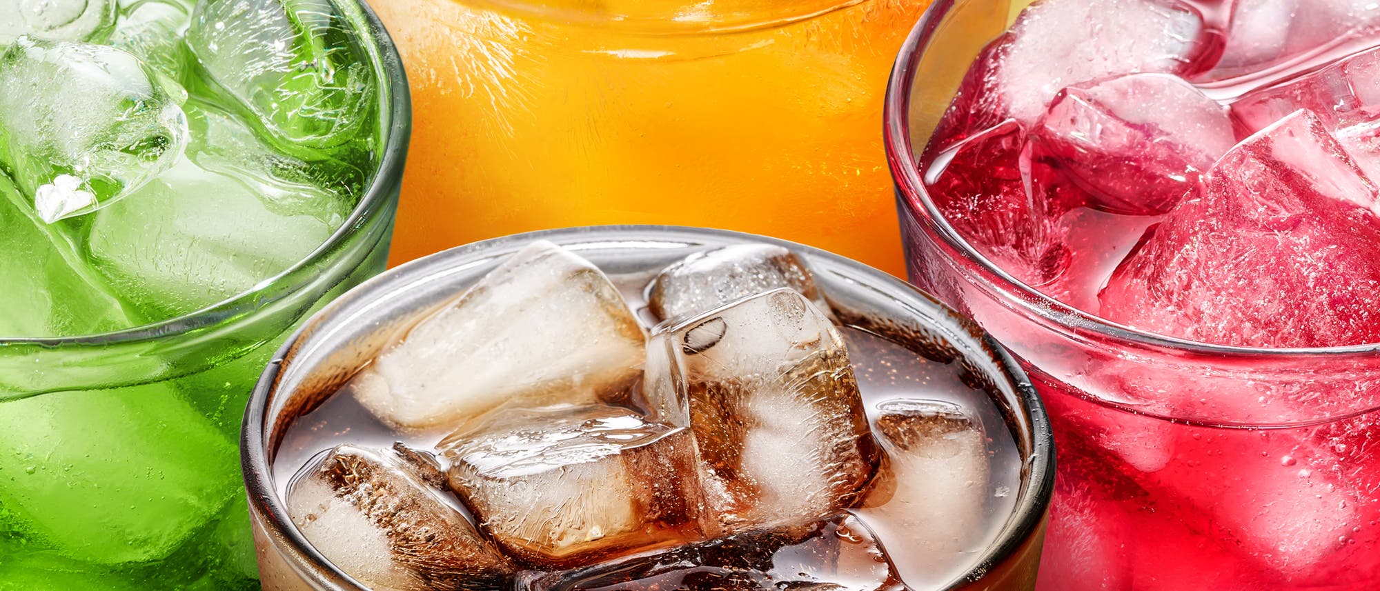 Vier Gläser mit verschiedenen farbigen Getränken und Eiswürfeln. Das grüne Getränk ist links, das orangefarbene oben, das rote rechts und das braune Getränk unten in der Mitte. Die Gläser sind auf einem gelben Hintergrund angeordnet. Vier Gläser mit verschiedenen farbigen Getränken und Eiswürfeln. Das grüne Getränk ist links, das orangefarbene oben, das rote rechts und das braune Getränk unten in der Mitte. Die Gläser sind auf einem gelben Hintergrund angeordnet.
