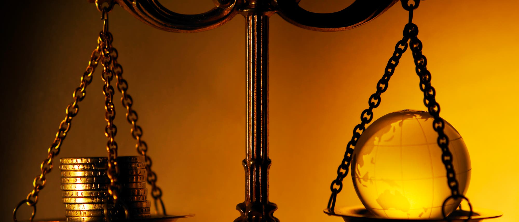 Altmodische Balkenwaage mit Münzen in der einen Schale und einem gläsernen Globus in der anderen. Altmodische Balkenwaage mit Münzen in der einen Schale und einem gläsernen Globus in der anderen.