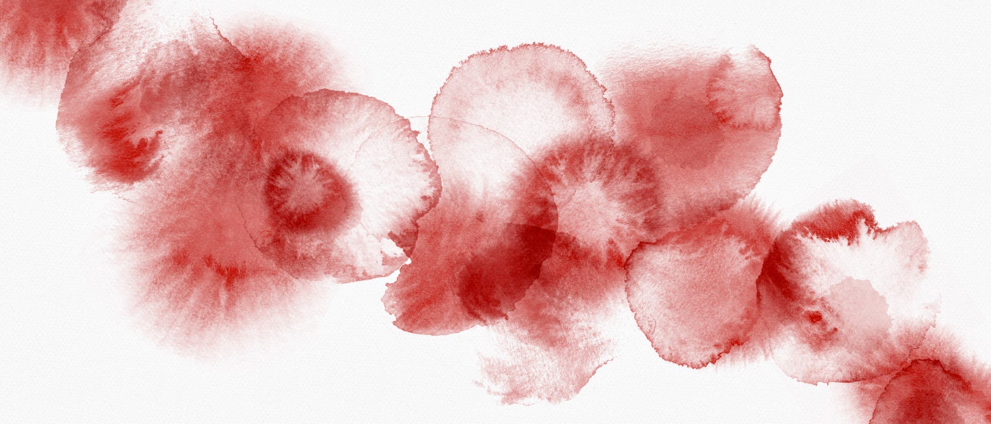 Hellrote Tropfen, die symbolisch für die Menstruationsblutung stehen.