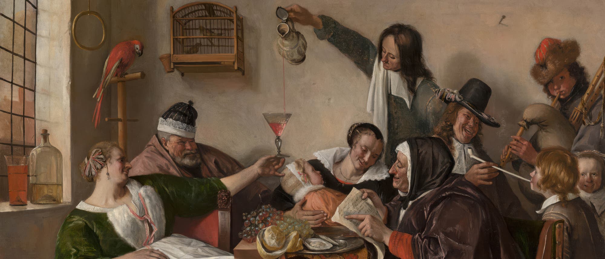 Ein Gem&auml;lde einer lebhaften Szene in einem Innenraum, die eine Gruppe von Menschen zeigt, die an einem Tisch sitzen und feiern. Eine Frau in einem gr&uuml;nen Kleid h&auml;lt ein Glas, w&auml;hrend ein Mann Wein einschenkt. Auf dem Tisch liegen Trauben und ein Brotlaib. Ein Hund steht aufmerksam daneben. Im Hintergrund spielt ein Musiker ein Blasinstrument. Ein Papagei sitzt auf einem Regal, und ein Vogelk&auml;fig h&auml;ngt an der Wand. Die Atmosph&auml;re ist fr&ouml;hlich und gesellig.