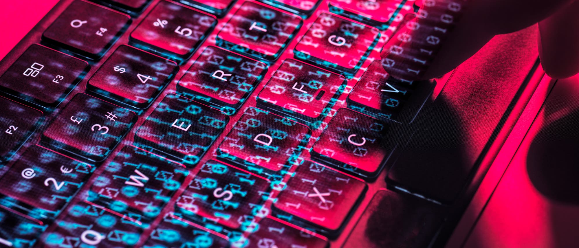 Eine beleuchtete Computertastatur mit &uuml;berlagerten Bin&auml;rcode-Zahlen in Blau und Rot. Eine Hand tippt auf die Tasten, was auf das Thema Cyber-Sicherheit oder Datenverarbeitung hinweist. Die Farben und der Code erzeugen eine futuristische Atmosph&auml;re.