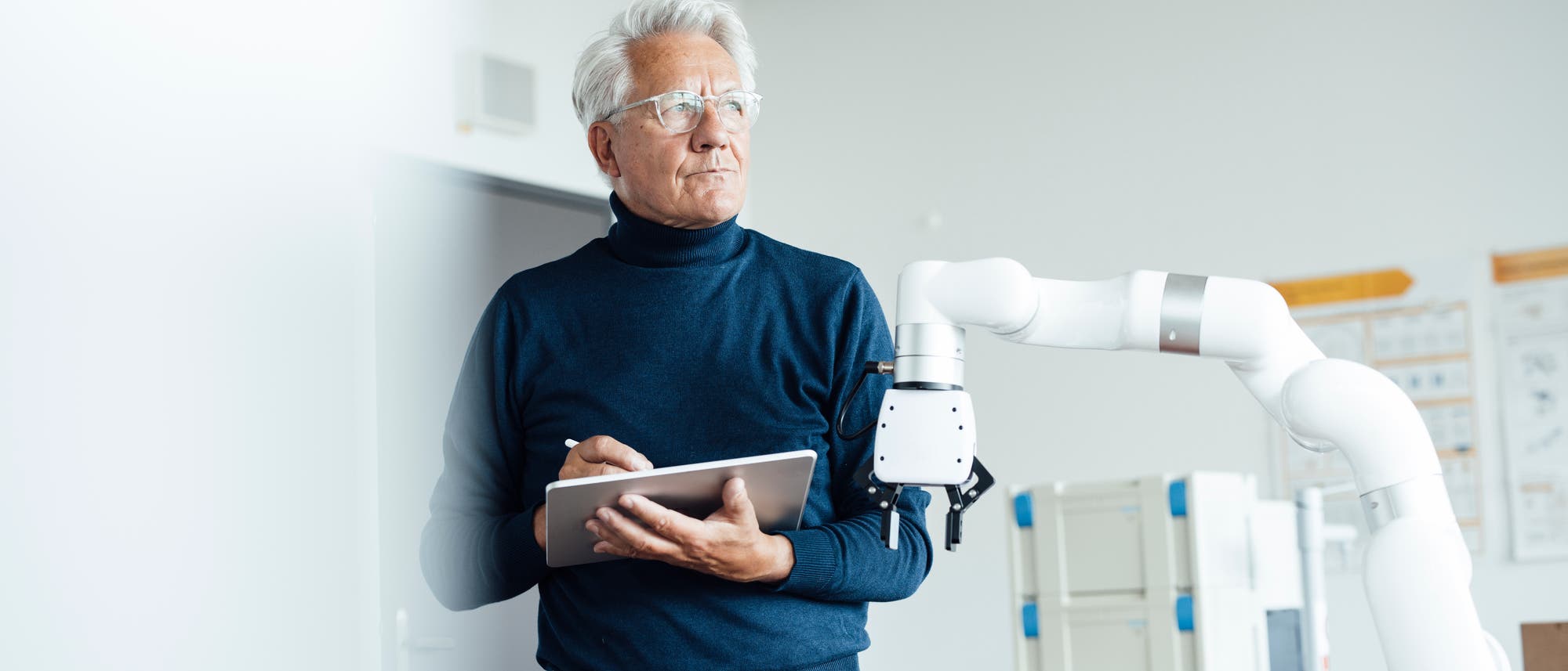 Eine Person steht in einem modernen Labor und hält ein Tablet in der Hand. Neben ihr befindet sich ein weißer Roboterarm. Die Person trägt einen dunklen Rollkragenpullover und eine Brille und blickt nachdenklich in die Ferne. Im Hintergrund sind unscharfe technische Geräte und Poster an der Wand zu sehen. Die Szene vermittelt einen Eindruck von Technologie und Forschung. Eine Person steht in einem modernen Labor und hält ein Tablet in der Hand. Neben ihr befindet sich ein weißer Roboterarm. Die Person trägt einen dunklen Rollkragenpullover und eine Brille und blickt nachdenklich in die Ferne. Im Hintergrund sind unscharfe technische Geräte und Poster an der Wand zu sehen. Die Szene vermittelt einen Eindruck von Technologie und Forschung.