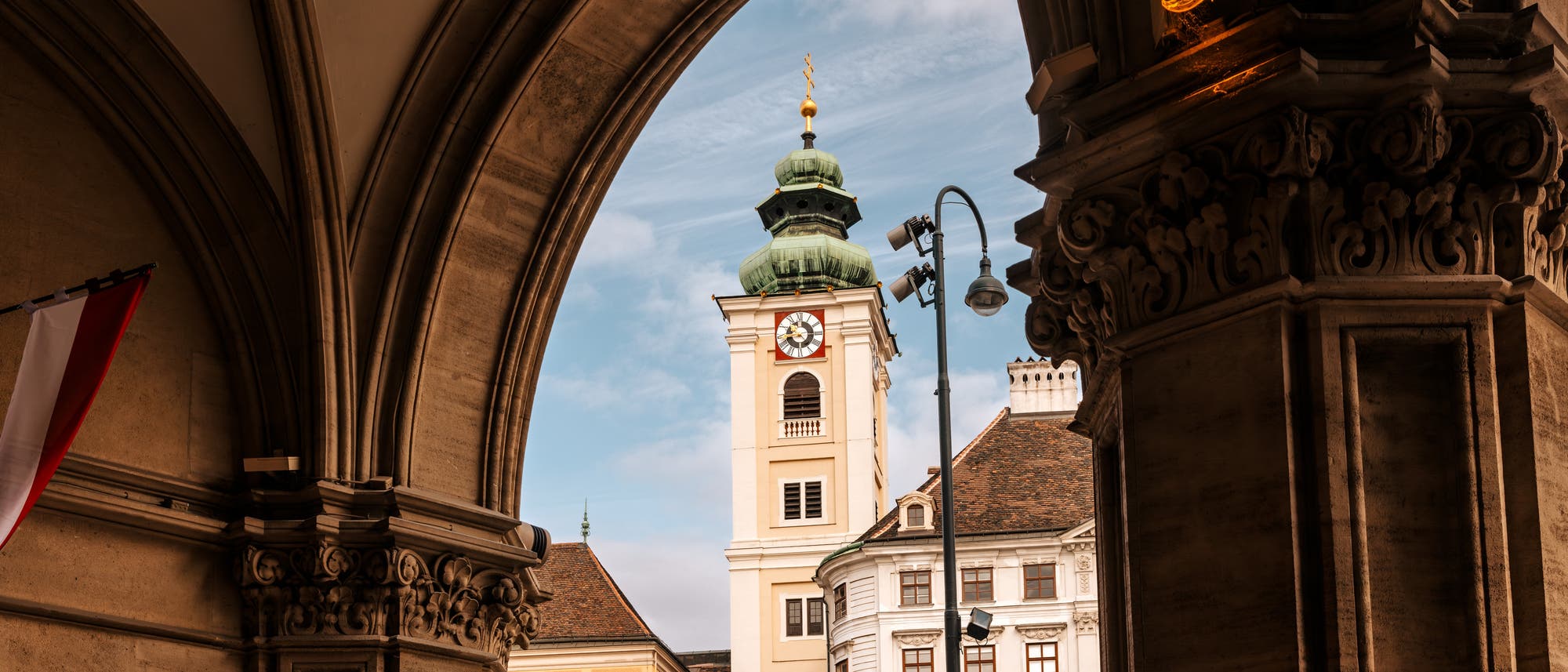 Blick aus einem Säulengang auf den Kirchturm der Schottenkirche in Wiens historischem Zentrum Blick aus einem Säulengang auf den Kirchturm der Schottenkirche in Wiens historischem Zentrum