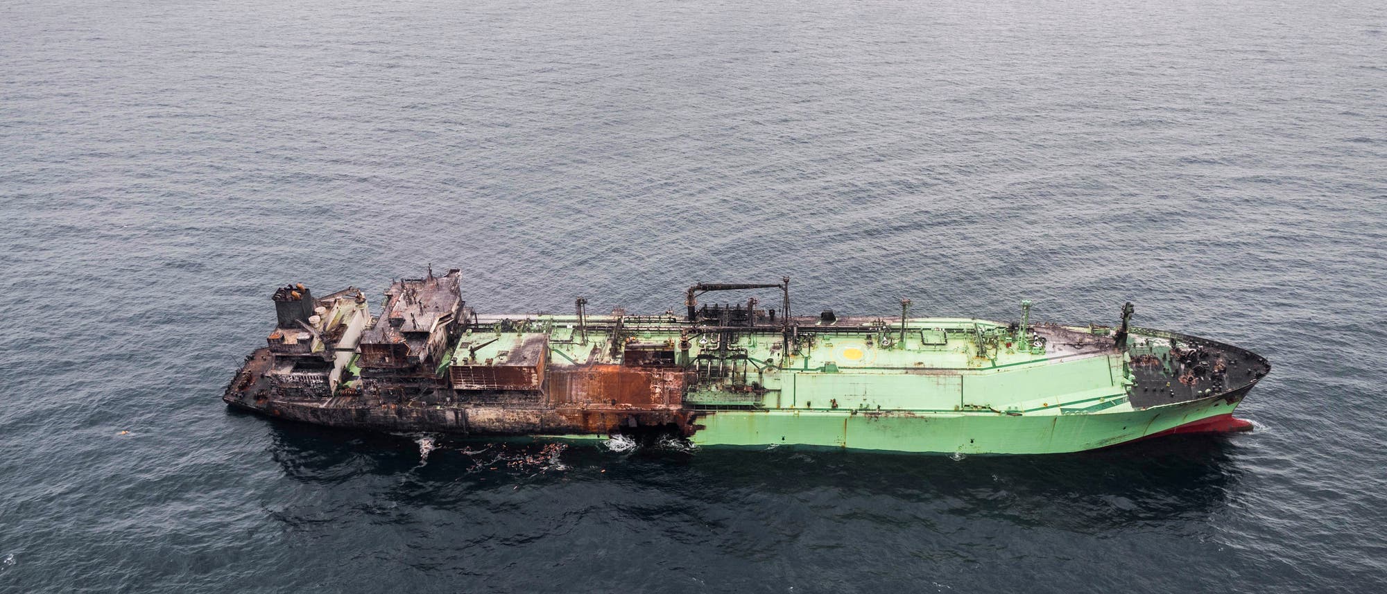 Ein verrostetes und beschädigtes Schiff treibt auf dem offenen Meer. Die Struktur des Schiffs ist stark beschädigt, mit sichtbaren Roststellen und zerstörten Aufbauten. Das Wasser um das Schiff ist ruhig, und der Himmel ist bewölkt. Das Bild vermittelt den Eindruck von Verlassenheit und Verfall. Ein verrostetes und beschädigtes Schiff treibt auf dem offenen Meer. Die Struktur des Schiffs ist stark beschädigt, mit sichtbaren Roststellen und zerstörten Aufbauten. Das Wasser um das Schiff ist ruhig, und der Himmel ist bewölkt. Das Bild vermittelt den Eindruck von Verlassenheit und Verfall.