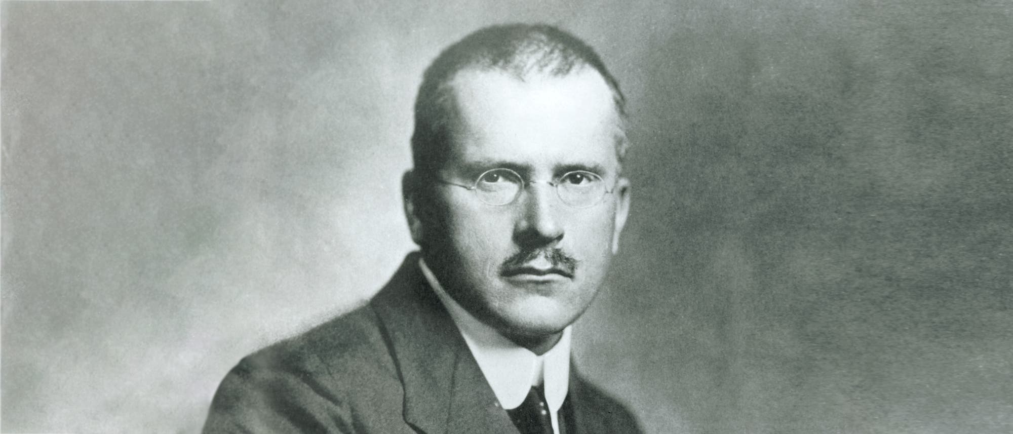 Ein Schwarz-Weiß-Porträt eines Mannes mit Brille und Schnurrbart. Der Mann schaut direkt in die Kamera. Ein Schwarz-Weiß-Porträt eines Mannes mit Brille und Schnurrbart. Der Mann schaut direkt in die Kamera.