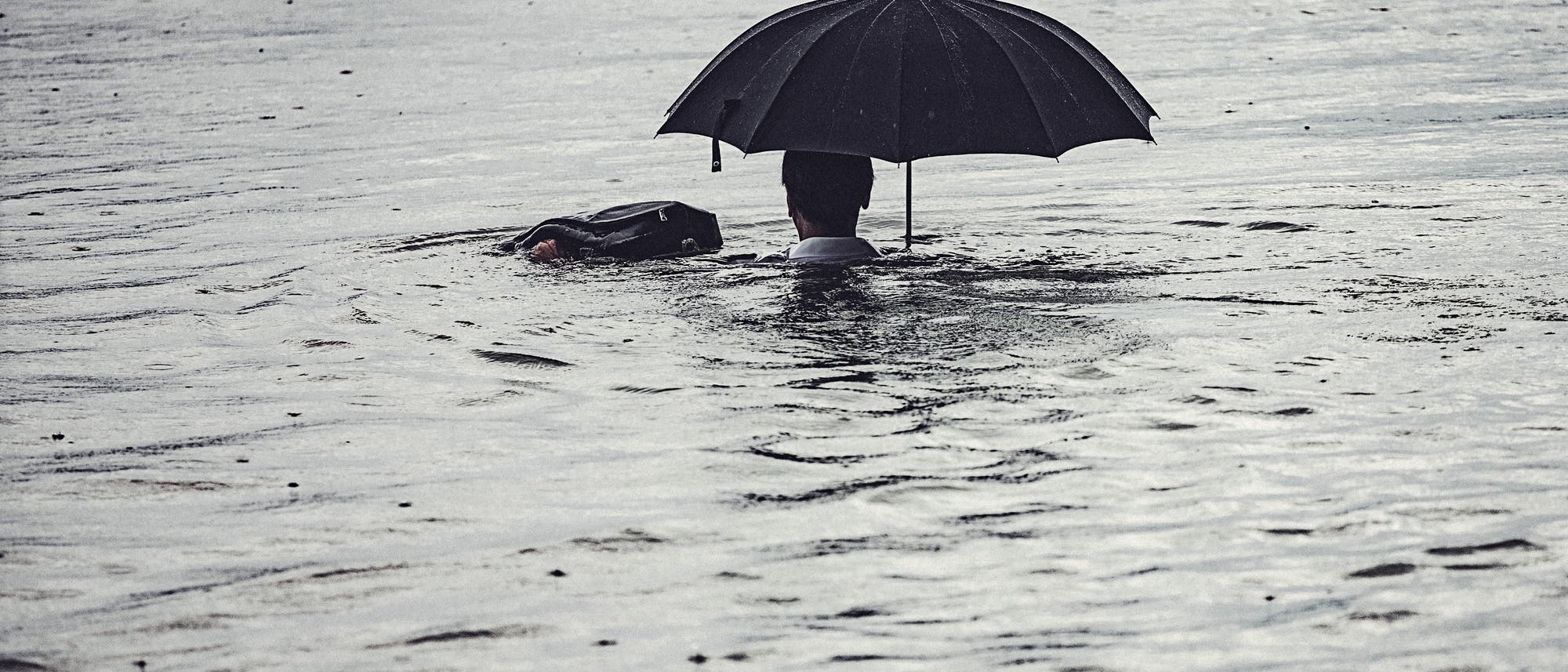 Mann mit Schirm im Wasser