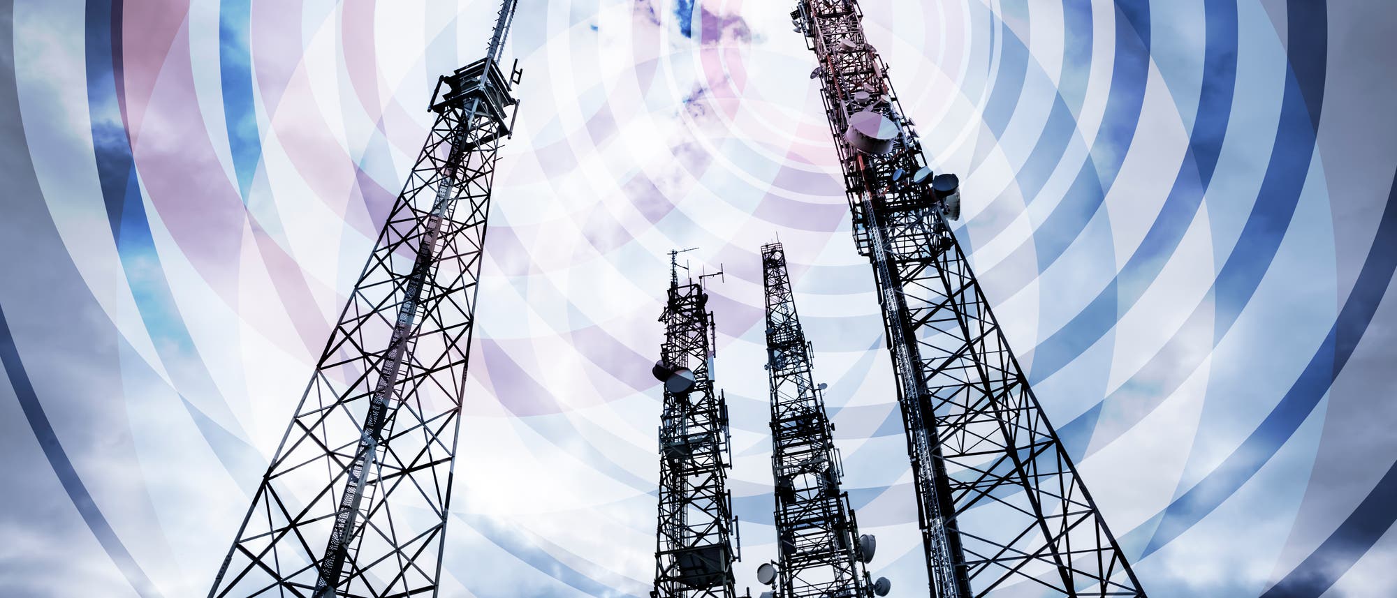 Mehrere hohe Sendemasten ragen in den bewölkten Himmel, umgeben von konzentrischen Kreisen, die Funkwellen darstellen. Die Masten sind mit verschiedenen Antennen und Satellitenschüsseln ausgestattet.