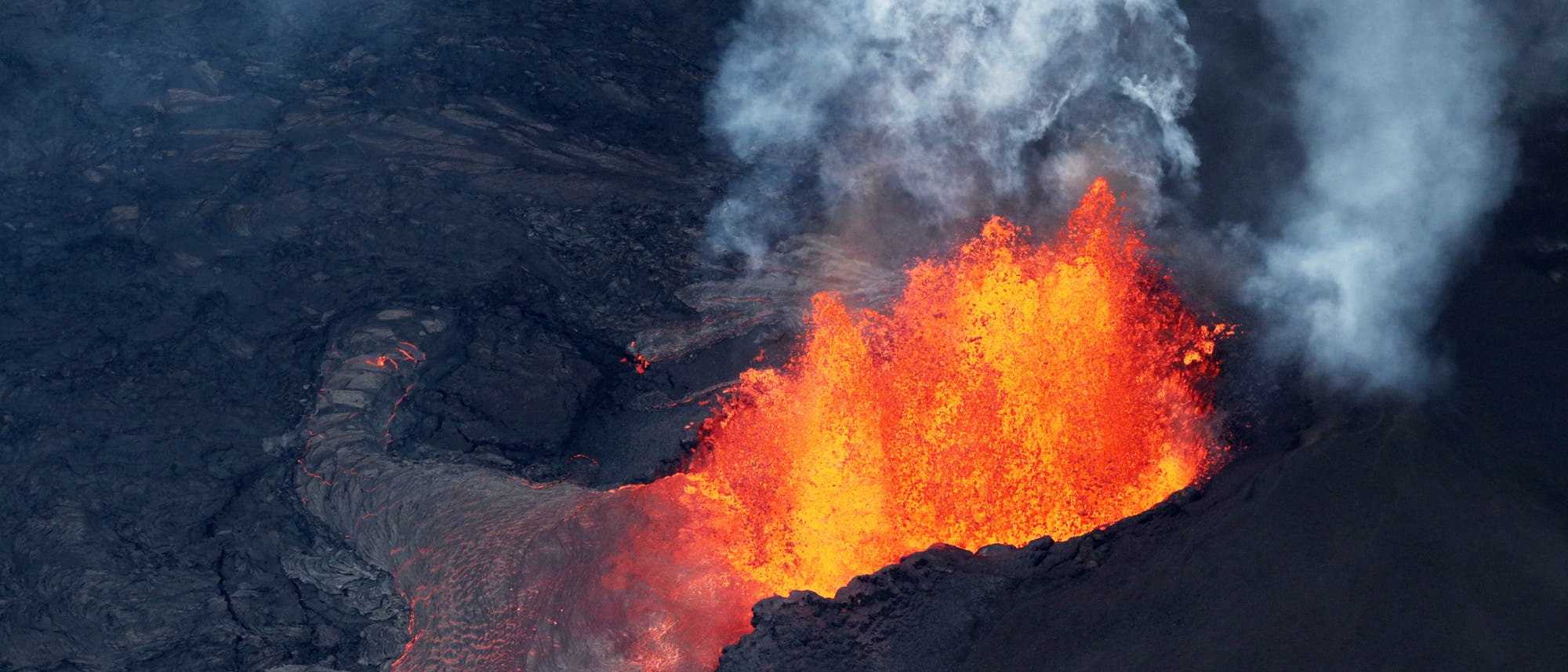 Ein aktiver Vulkan, der glühende Lava und Rauch in die Luft schleudert. Die Lava fließt über die dunkle, erkaltete Oberfläche des Vulkans. Keine Menschen sind im Bild zu sehen. Ein aktiver Vulkan, der glühende Lava und Rauch in die Luft schleudert. Die Lava fließt über die dunkle, erkaltete Oberfläche des Vulkans. Keine Menschen sind im Bild zu sehen.