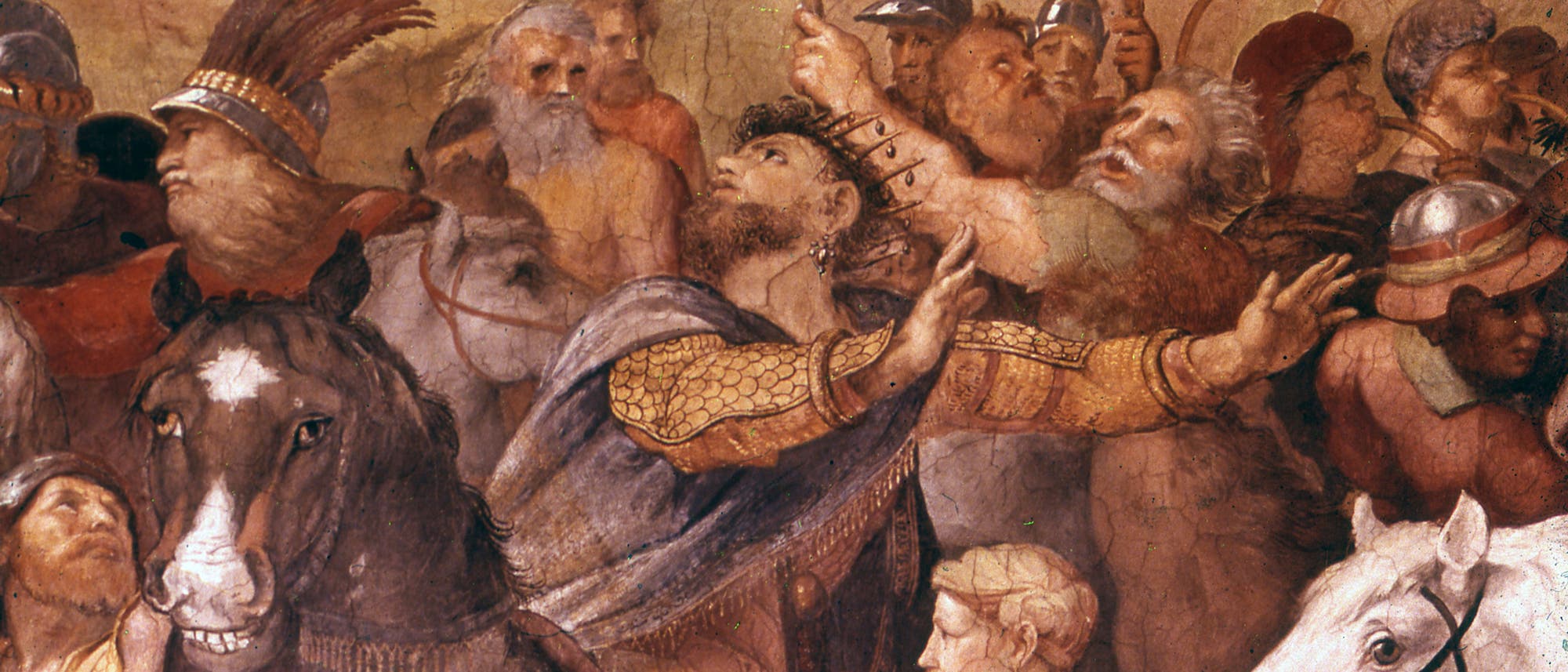 Eine historische Wandmalerei zeigt eine Gruppe von Menschen in mittelalterlicher Kleidung, die in einer dynamischen Szene versammelt sind. Einige tragen Helme und R&uuml;stungen, w&auml;hrend andere mit erhobenen Armen gestikulieren. Im Vordergrund sind zwei Pferde zu sehen, eines davon mit einem Reiter. Die Figuren sind in lebhaften Farben gehalten, was der Szene Dramatik und Bewegung verleiht. Die Komposition vermittelt den Eindruck einer Versammlung oder eines Aufbruchs.