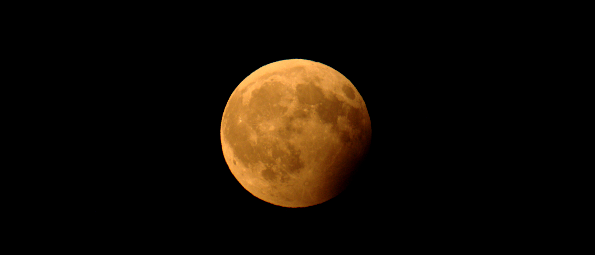 Foto des Mondes während einer partiellen Mondfinsternis, bei der ein Teil des Trabanten vom Kernschatten der Erde verdunkelt wird.