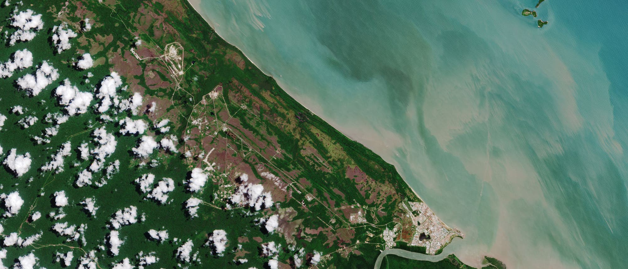 Der Weltraumbahnhof liegt nordwestlich der Stadt Kourou – inmitten weißer Sandstrände an der Atlantikküste und dichten tropischen Regenwalds, wie ein Bild des Copernicus-Satelliten »Sentinel 2« zeigt. 