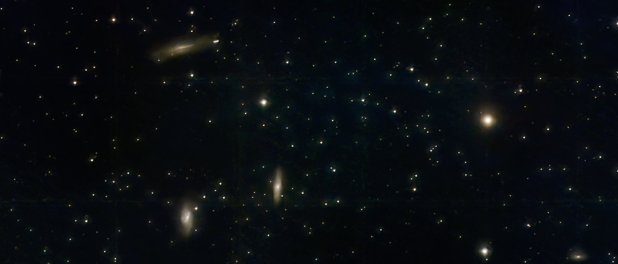 Eine astronomische Aufnahme zeigt einen Sternenhimmel mit mehreren Galaxien und Sternen. Die Galaxien sind als helle, l&auml;ngliche Flecken sichtbar und mit Bezeichnungen wie "NGC3596", "M65", "M66" und "NGC3593" markiert. Der Hintergrund ist dunkel, durchsetzt mit zahlreichen kleinen, leuchtenden Punkten, die Sterne darstellen. Die Galaxie "Flora" ist ebenfalls beschriftet. Das Bild vermittelt die Weite und Komplexit&auml;t des Universums.