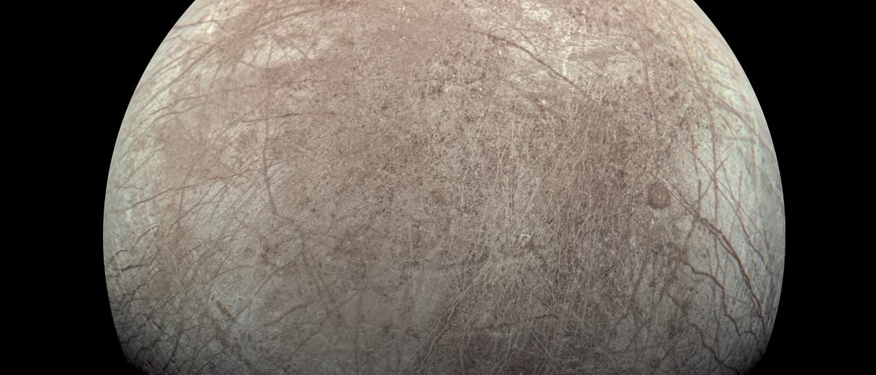 Eine detaillierte Aufnahme des Jupitermondes Europa, die seine eisige Oberfl&auml;che zeigt. Die Oberfl&auml;che ist von zahlreichen Rissen und Linien durchzogen, die auf geologische Aktivit&auml;ten hinweisen. Der Mond erscheint in einem hellen, beige-grauen Farbton vor einem schwarzen Hintergrund des Weltraums.