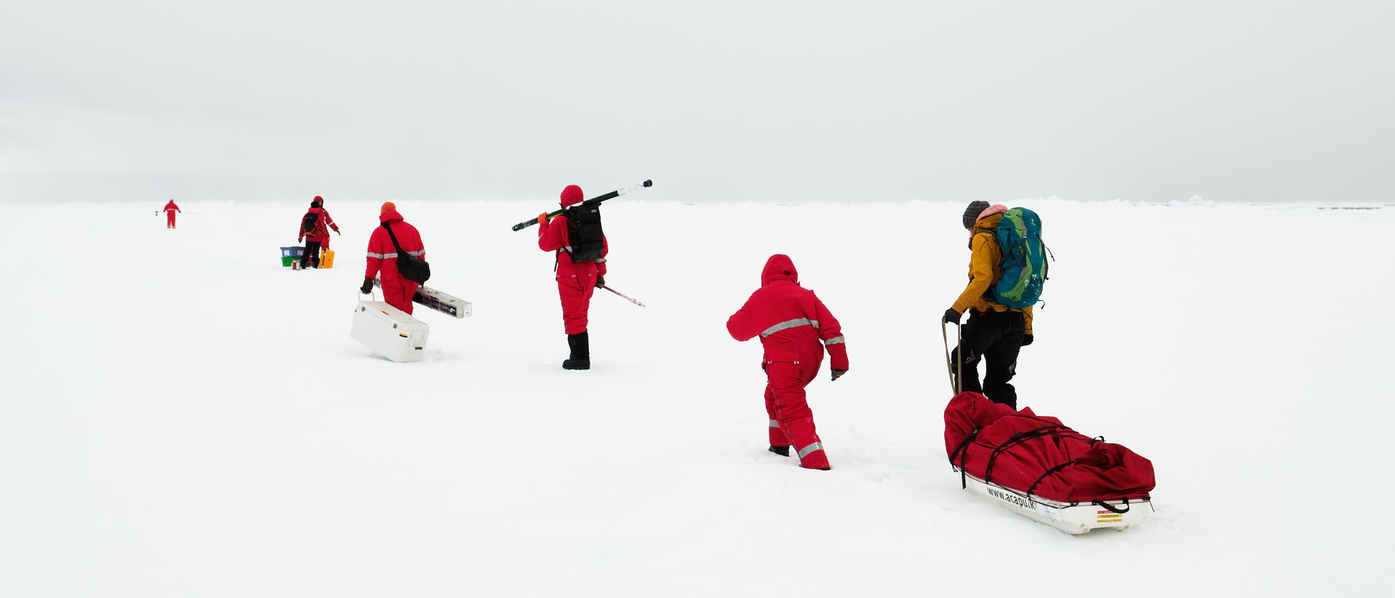 Menschen in roten Schneeanzügen stapfen durch Schnee
