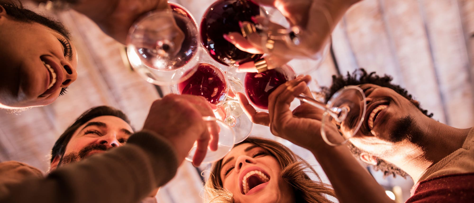 Eine bunt gemischte Gruppe trinkt fröhlich Rotwein