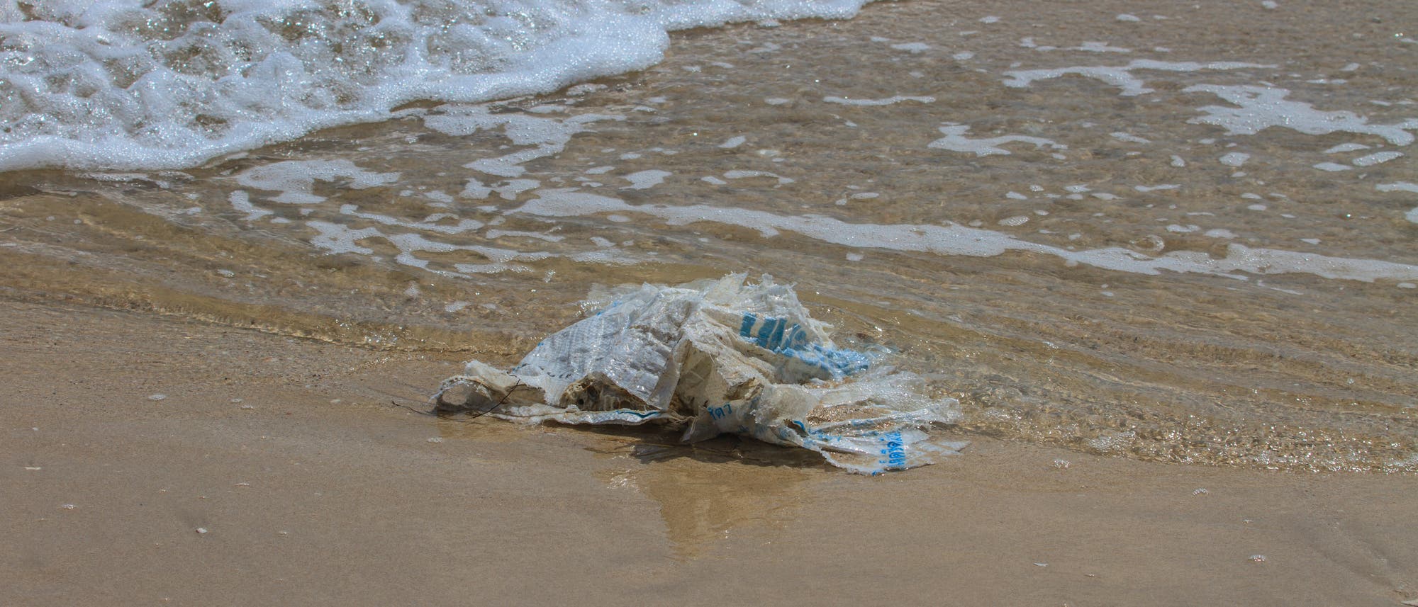 Eine Plastiktüte verschmutzt den Strand und belastet das Meer