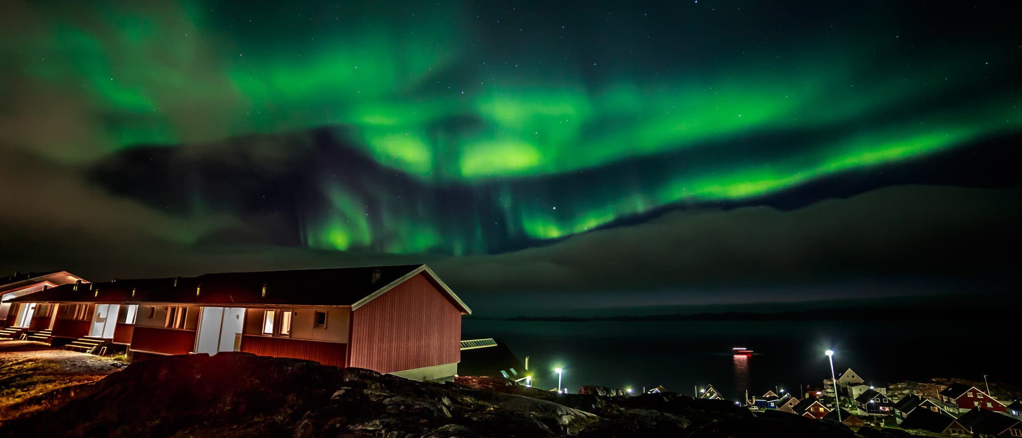 Polarlichter verzaubern die Nacht über einer grönländischen Siedlung
