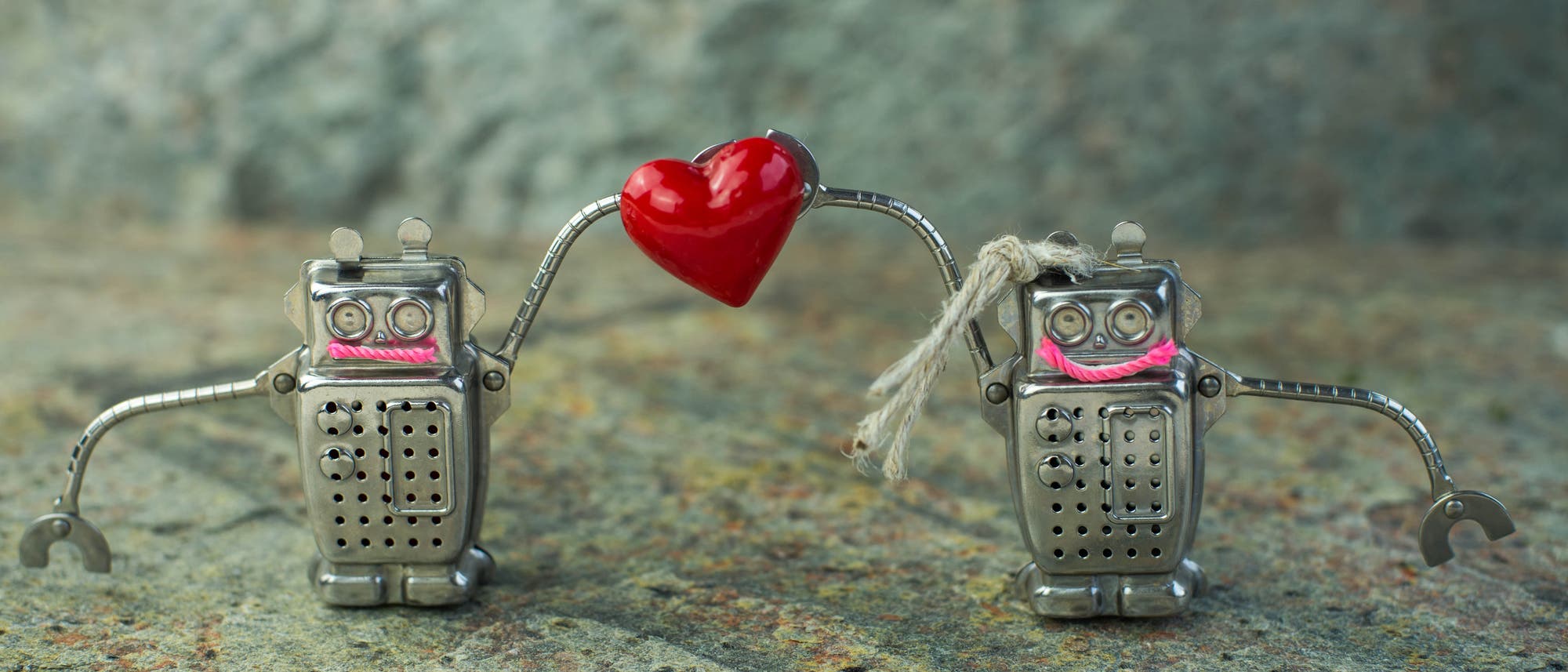 Zwei Blechroboter halten ein Herz hoch