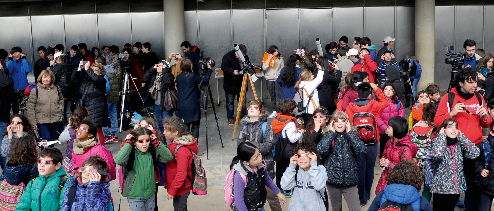 Schüler mit Teleskopen und Sonnenfinsternisbrillen