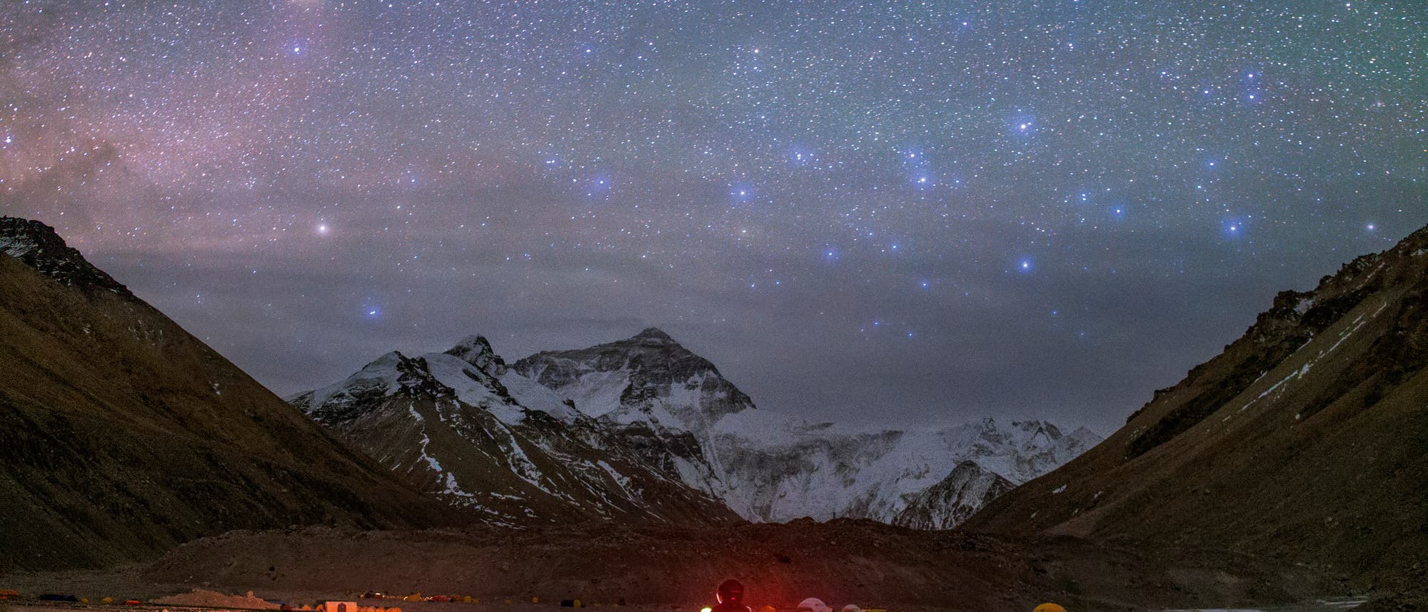 Der rötliche Antares im Sternbild Skorpion und die bläulichen Sterne des Centaurus leuchten über den hohen Berggipfeln des Himalaya. Der Motorrad-Tourist erreicht gerade das nördliche Basislager des Mount Everest in Tibet, das auf einer Höhe von 5170 Metern liegt.