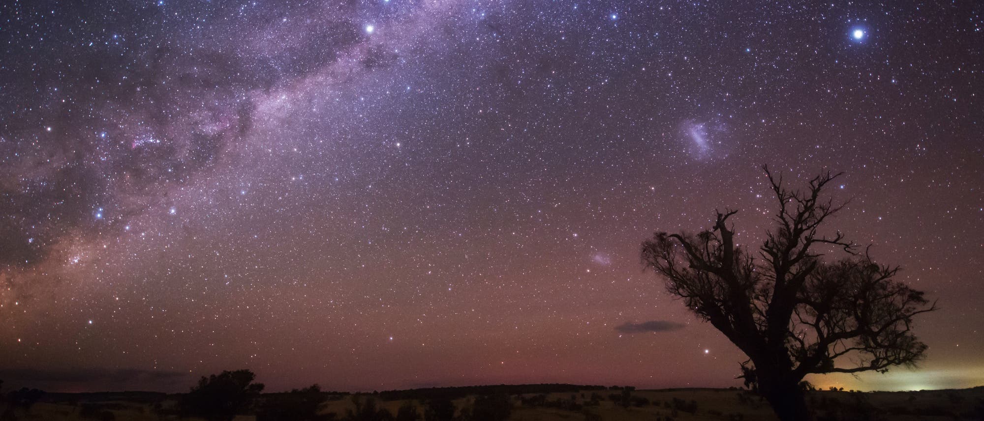 Die Milchstraße, die beiden Magellanschen Wolken und der Stern Canopus leuchten über den Weiten des australischen Outback.
