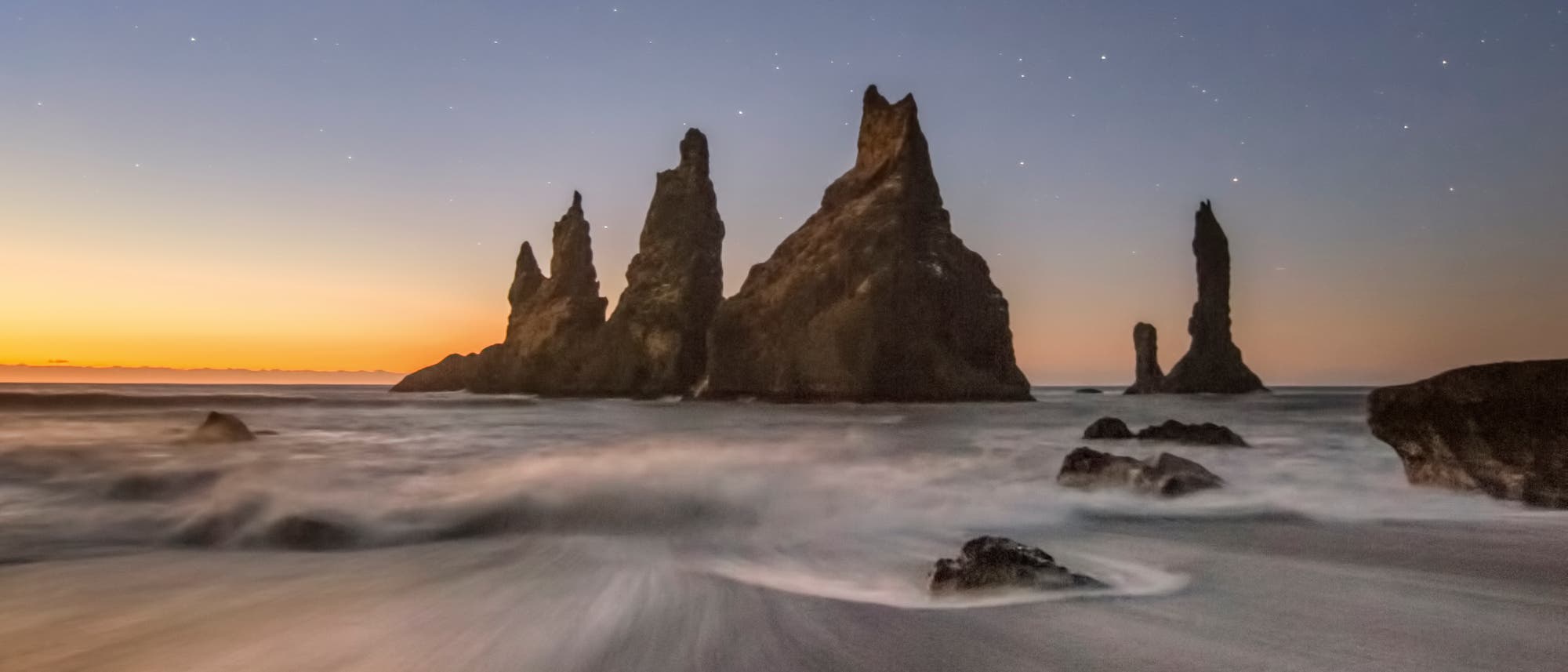 Vor der Südküste Islands ragen schwarze Felsspitzen aus dem Meer. Einer Legende nach wurde eine Gruppe von gierigen Trollen bei dem Versuch, ein gestrandetes Schiff auszurauben, von der aufgehenden Morgensonne überrascht, und sie erstarrten zu Stein.