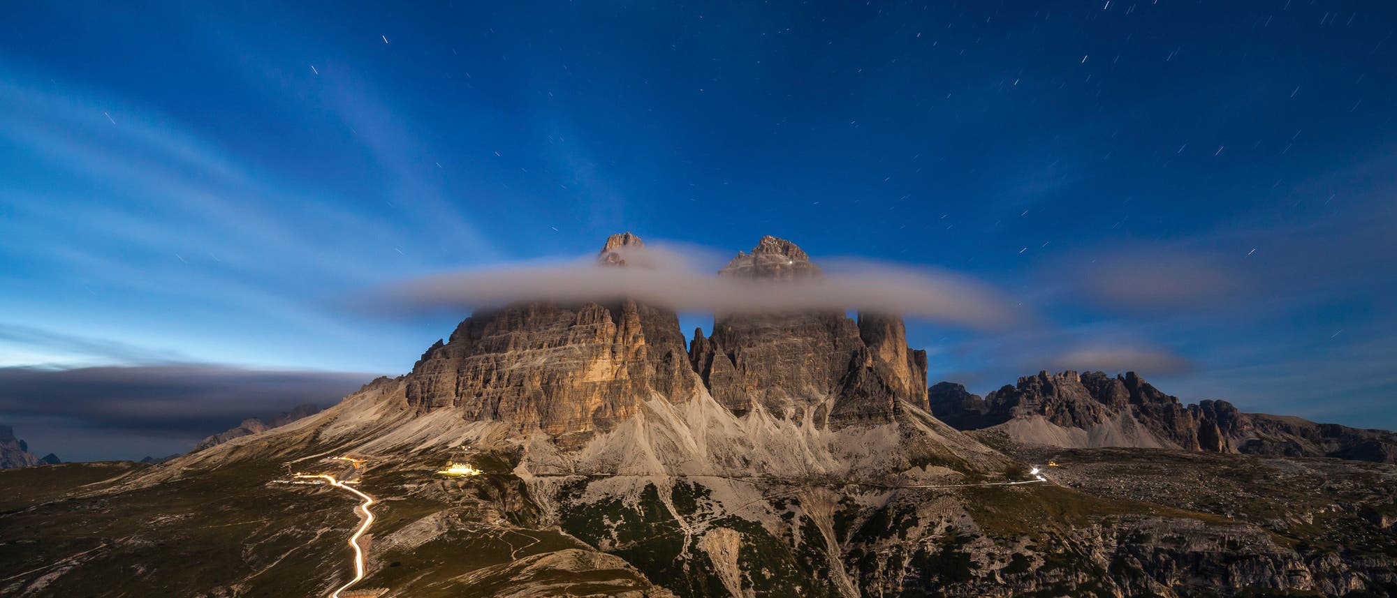 Wolken legen sie sich wie eine Hutkrempe um die Gipfel der Drei Zinnen in den Dolomiten.