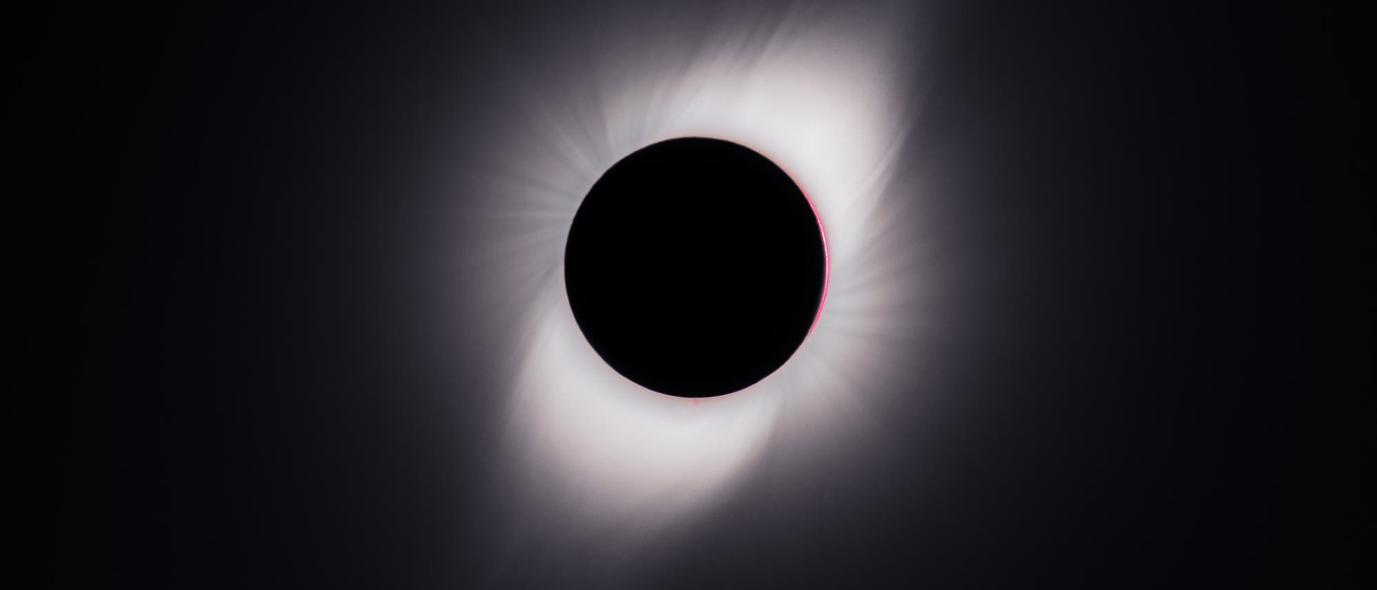 Eine totale Sonnenfinsternis, bei der der Mond die Sonne vollständig verdeckt. Der dunkle Mond ist von der leuchtenden Sonnenkorona umgeben, die in einem strahlenden Ring sichtbar ist. Der Hintergrund ist dunkel, was den Kontrast zur hellen Korona verstärkt. Eine totale Sonnenfinsternis, bei der der Mond die Sonne vollständig verdeckt. Der dunkle Mond ist von der leuchtenden Sonnenkorona umgeben, die in einem strahlenden Ring sichtbar ist. Der Hintergrund ist dunkel, was den Kontrast zur hellen Korona verstärkt.