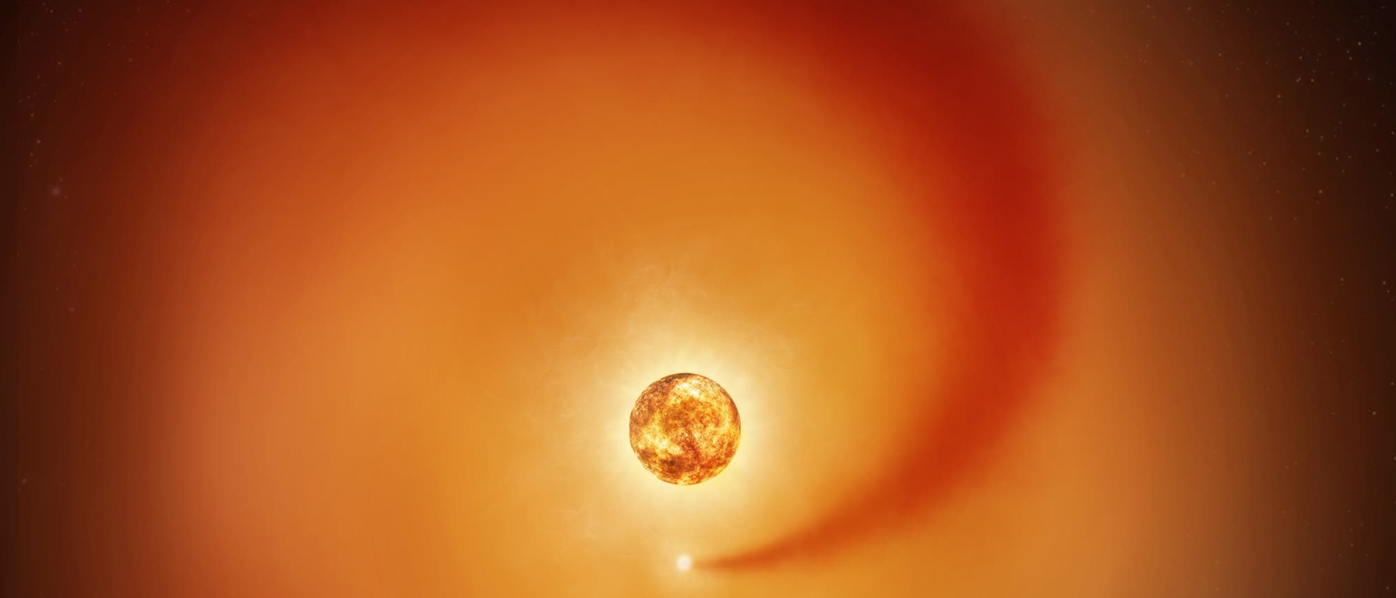 Eine k&uuml;nstlerische Darstellung eines roten Riesensterns im Weltraum, umgeben von einer leuchtenden, orangefarbenen H&uuml;lle aus Gas und Staub. Ein kleinerer, heller Punkt zieht eine lange, geschwungene Spur hinter sich her, die auf eine Wechselwirkung mit dem Stern hindeutet. Der Hintergrund zeigt einen dunklen, sternen&uuml;bers&auml;ten Himmel.