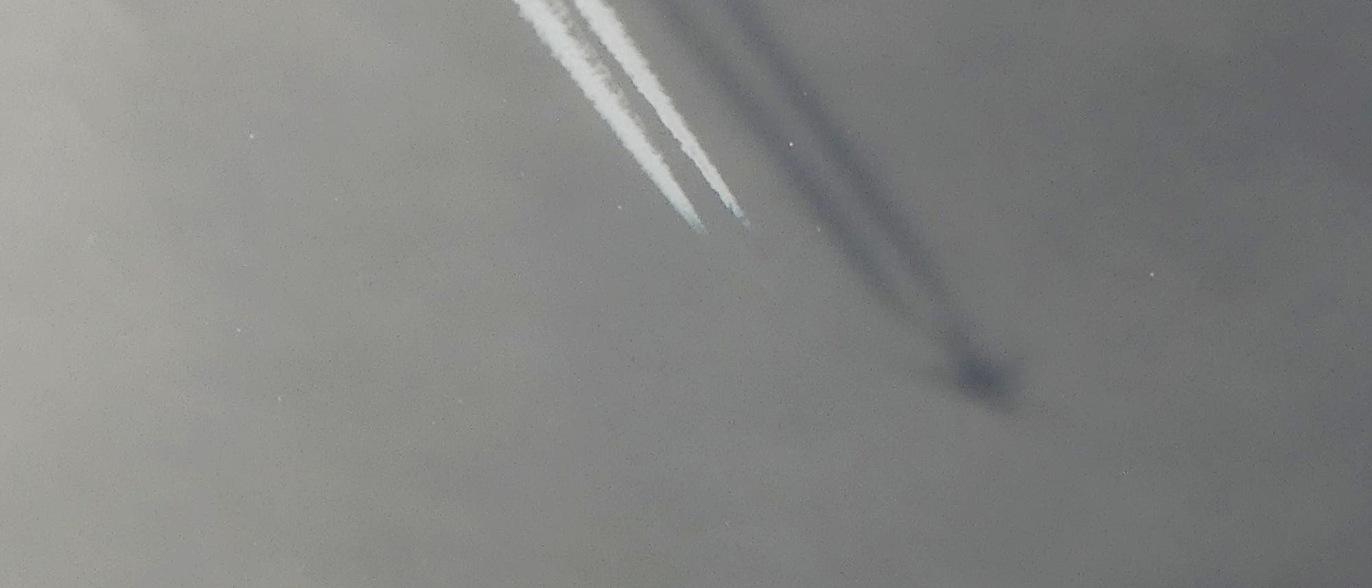 Zwei lange, weiße Kondensstreifen erstrecken sich diagonal über das Bild. Die Kondensstreifen werfen einen Schatten auf die darunter liegende Wolkendecke. Im Schatten ist das Flugzeug zu erkennen, das vor den eigentlichen Kondensstreifen nicht auszumachen ist. Zwei lange, weiße Kondensstreifen erstrecken sich diagonal über das Bild. Die Kondensstreifen werfen einen Schatten auf die darunter liegende Wolkendecke. Im Schatten ist das Flugzeug zu erkennen, das vor den eigentlichen Kondensstreifen nicht auszumachen ist.